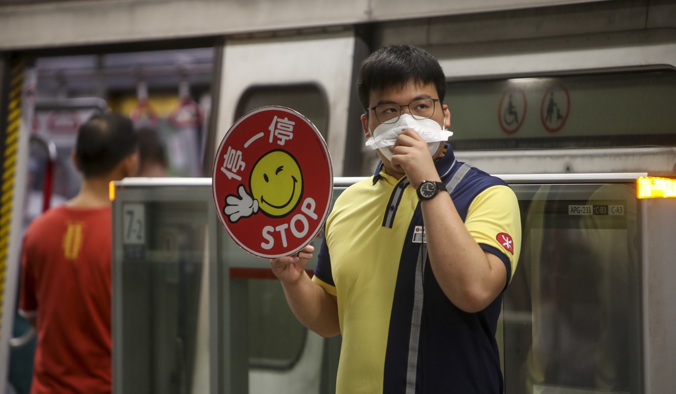 An MTR worker covers his mouth as he helps send off a train at a station mired by tear gas. Photo: Winson Wong
