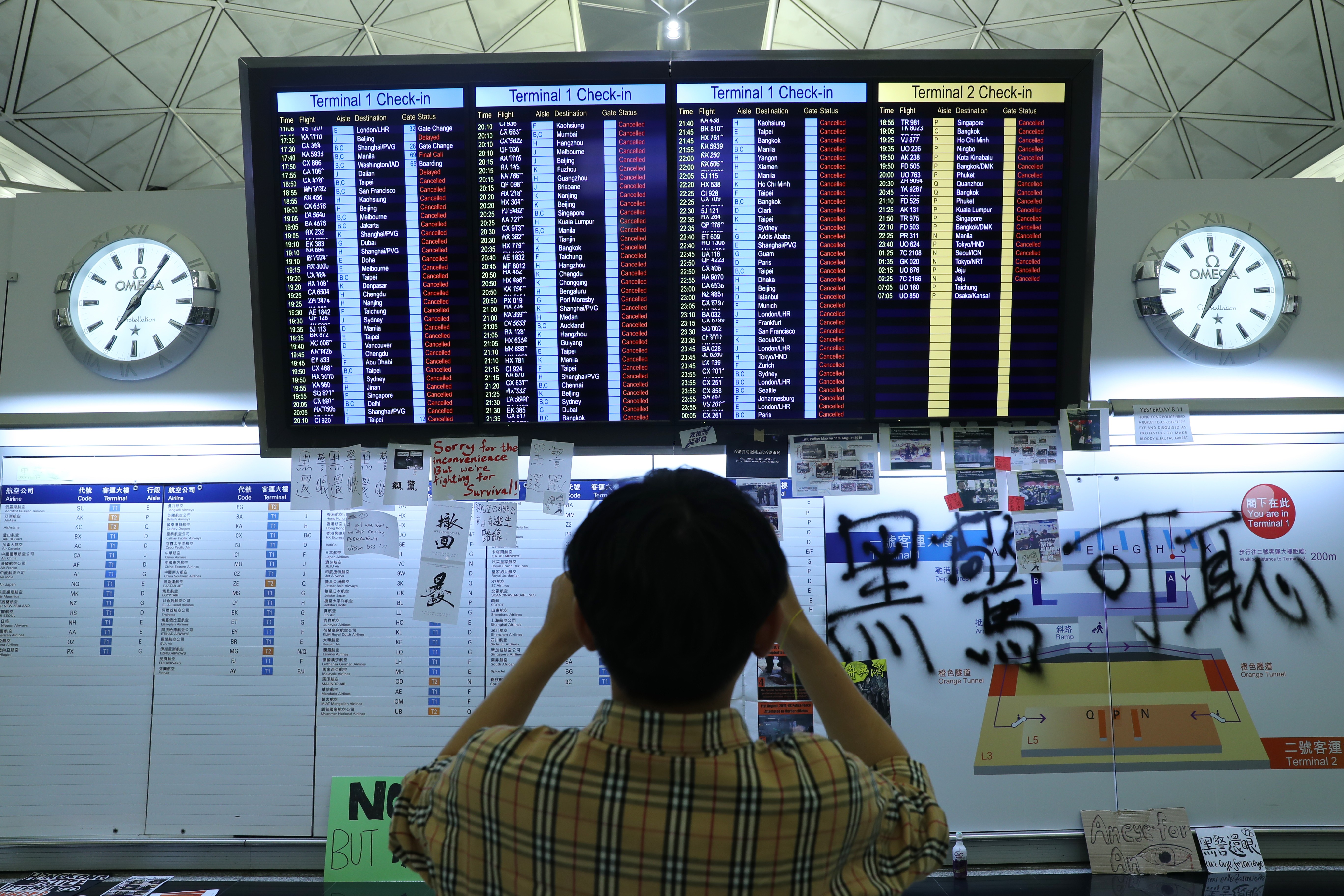 A tourist in front of the electronic board showing cancelled flights at the Hong Kong International Airport at Chek Lap Kok on August 12, 2019, as anti-government protesters occupied the airport, forcing authorities to cancel hundreds of outbound and inbound flights. Graffiti by protesters were scribbled in the right-hand corner. Photo: SCMP / Sam Tsang