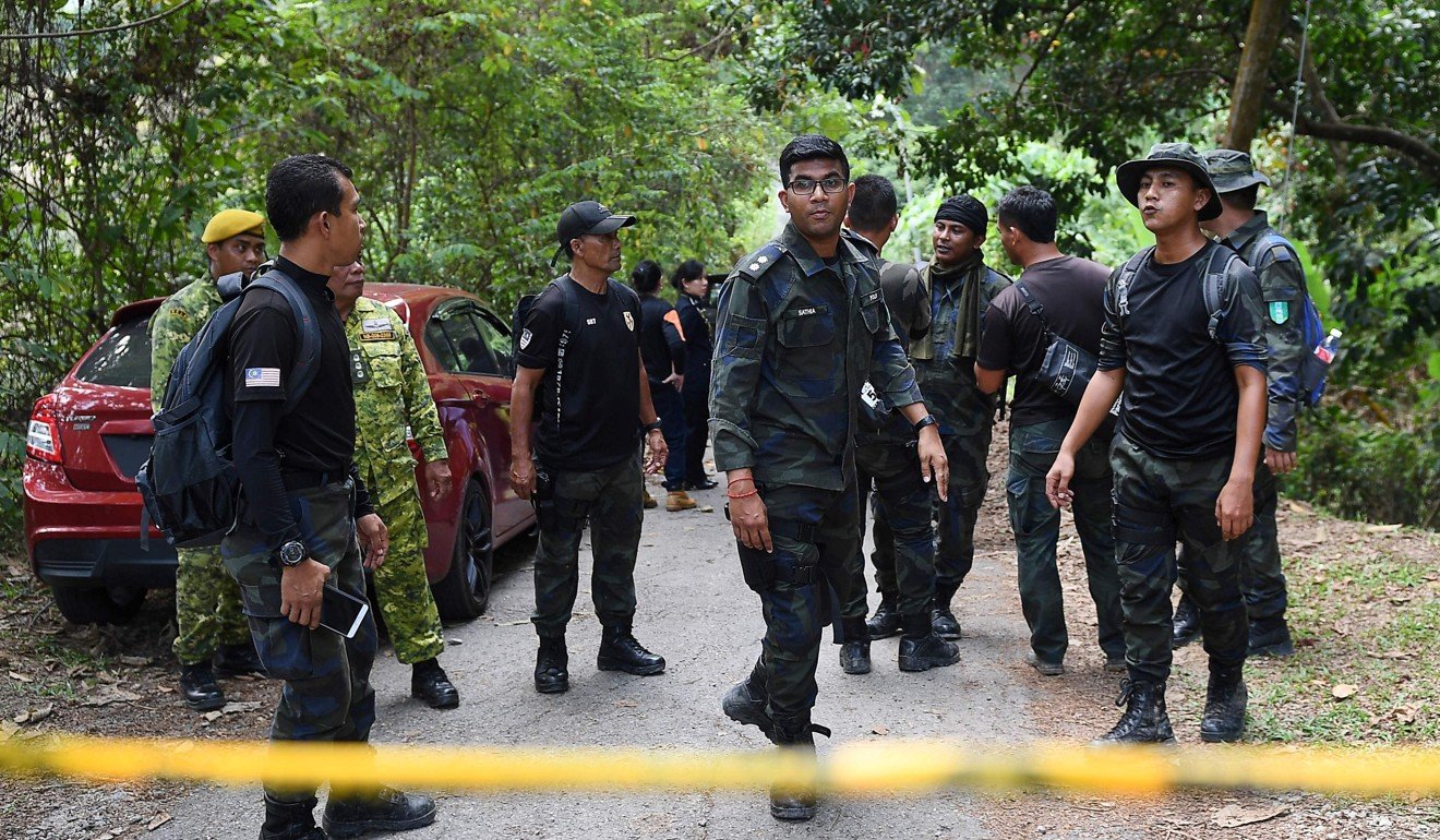 Members of a rescue team are seen behind a police line at the Dusun Resort. Photo: AFP