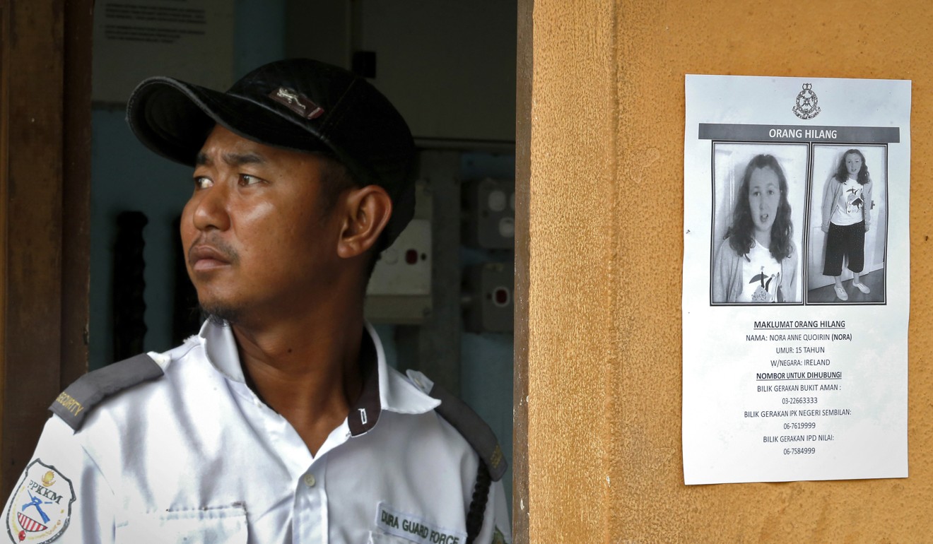 A security guard stands next to a notice showing the missing girl. Photo: AP