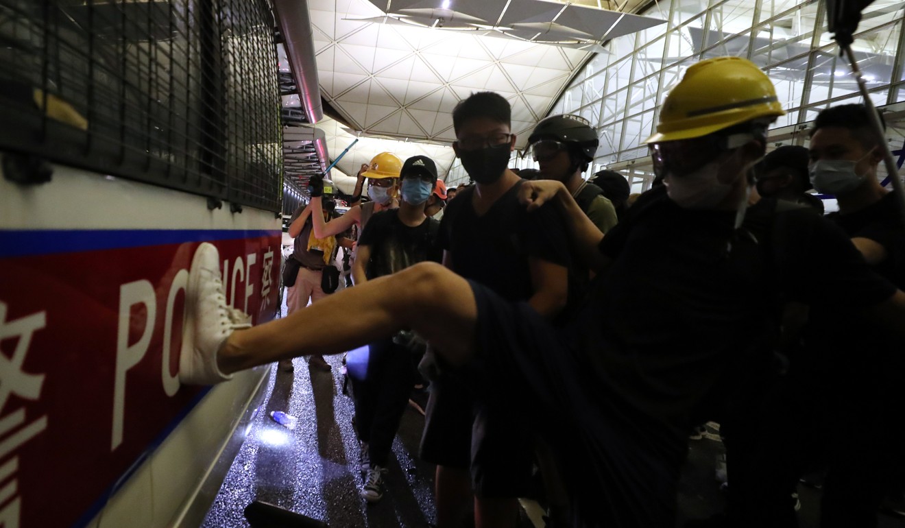 Anti-government protesters kick a police van outside the terminal at Hong Kong International Airport. Photo: Sam Tsang
