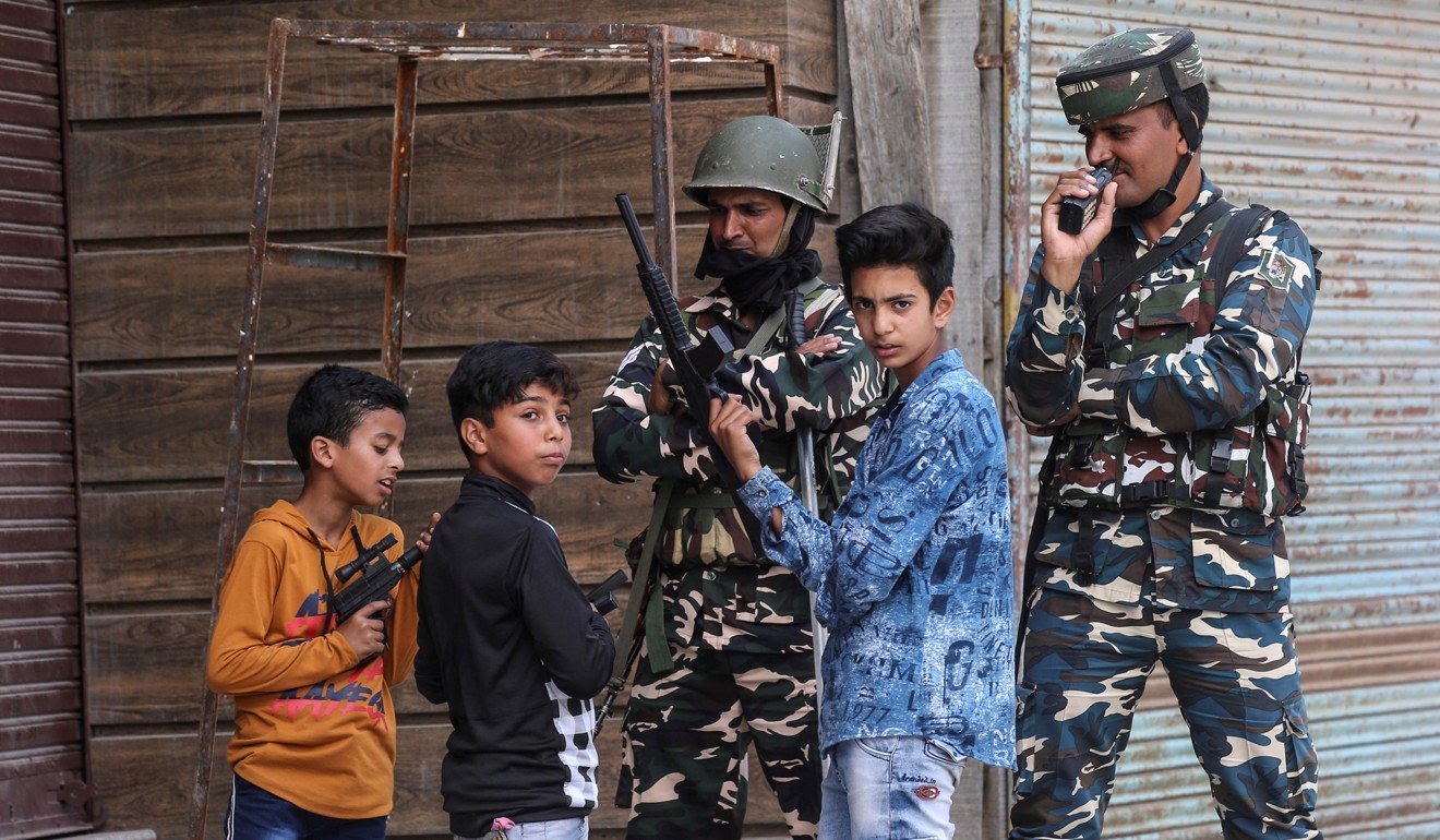 Children play with toy guns next to Indian security personnel. Photo: Reuters
