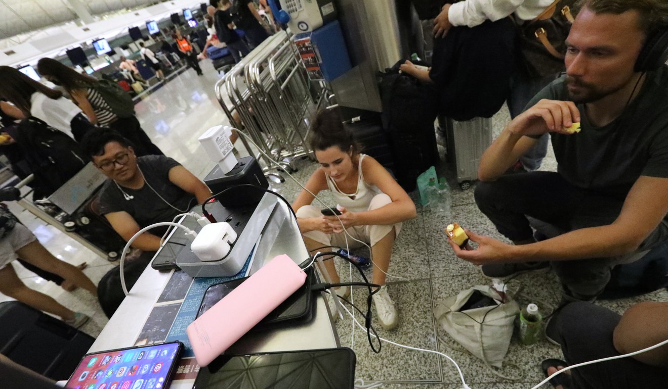 Stranded travellers charge their devices at Hong Kong International Airport on Tuesday. Photo: Felix Wong