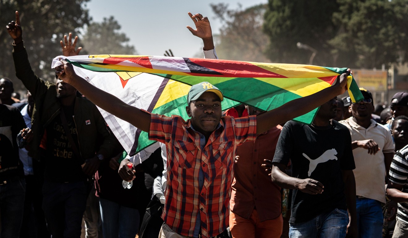 A man holding Zimbabwe’s national flag marches with other protesters in Harare on Friday. Photo: AFP
