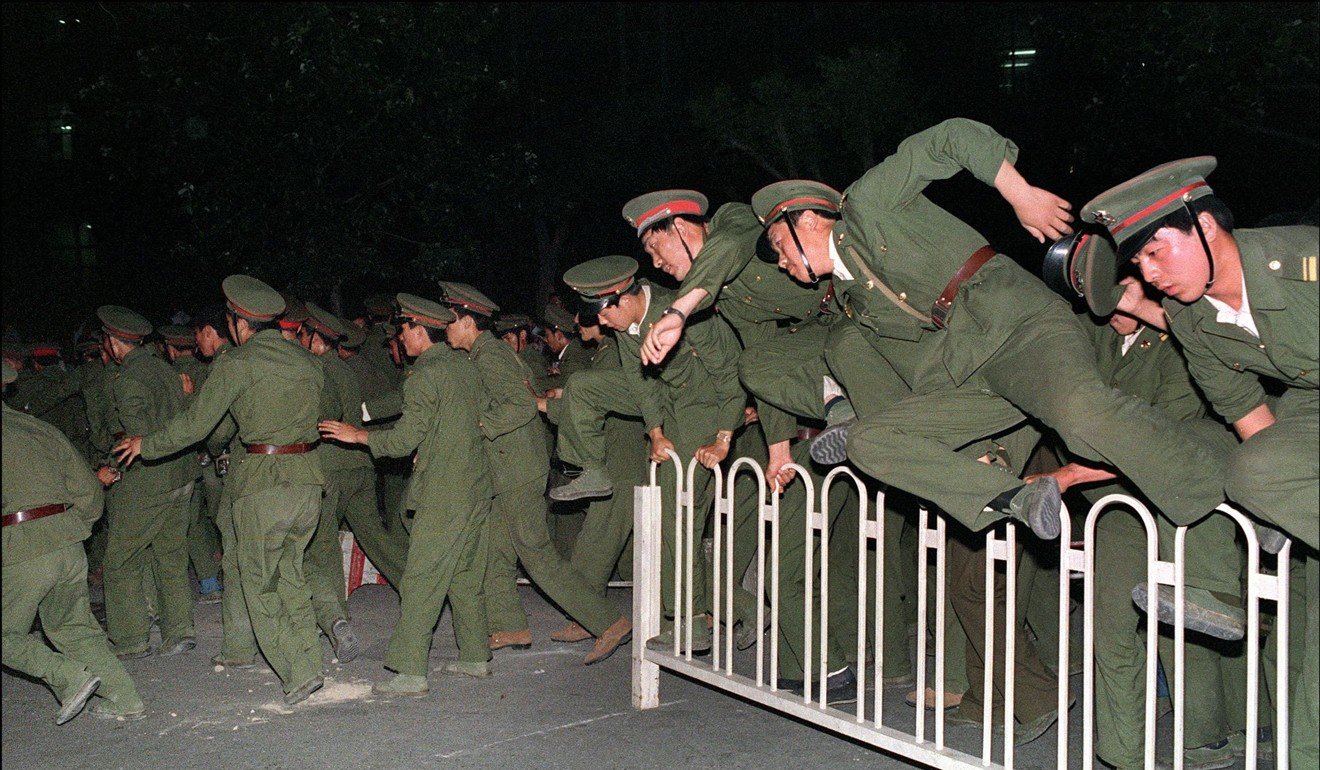 PLA soldiers leap over a barrier at Tiananmen Square in Beijing on June 4, 1989. Photo: AFP