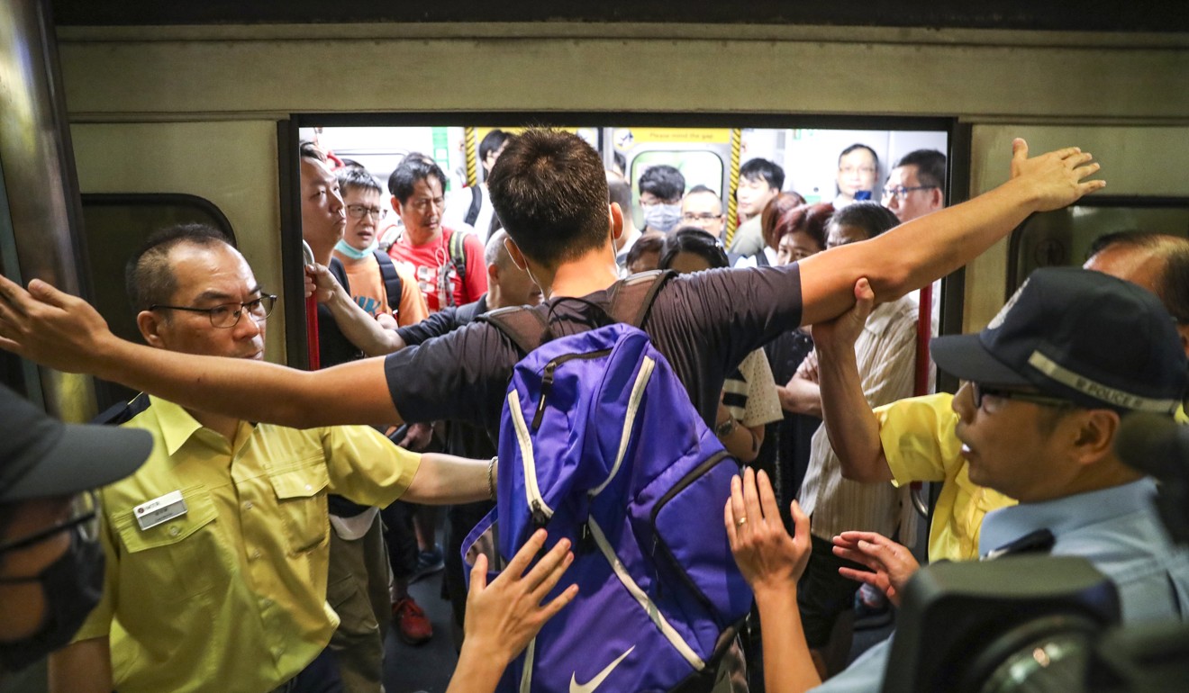 MTR staff try to stop a protester from disrupting train services at Tiu Kong Long station. Photo: Nora Tam