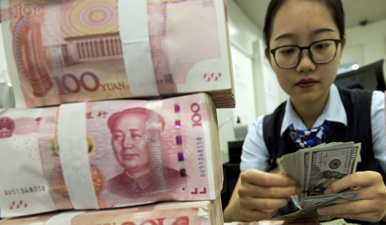 A bank employee counts US dollars next to stack of 100 yuan notes at a bank in Hai’an, eastern China’s Jiangsu province. Photo: AP
