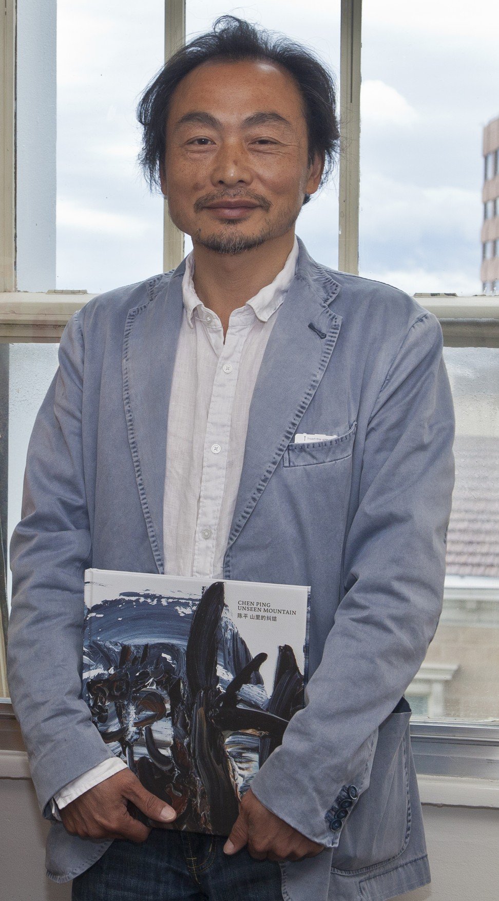 Chen with his book of paintings about Chinese tin miners in Tasmania. Photo: Tamara Thiessen