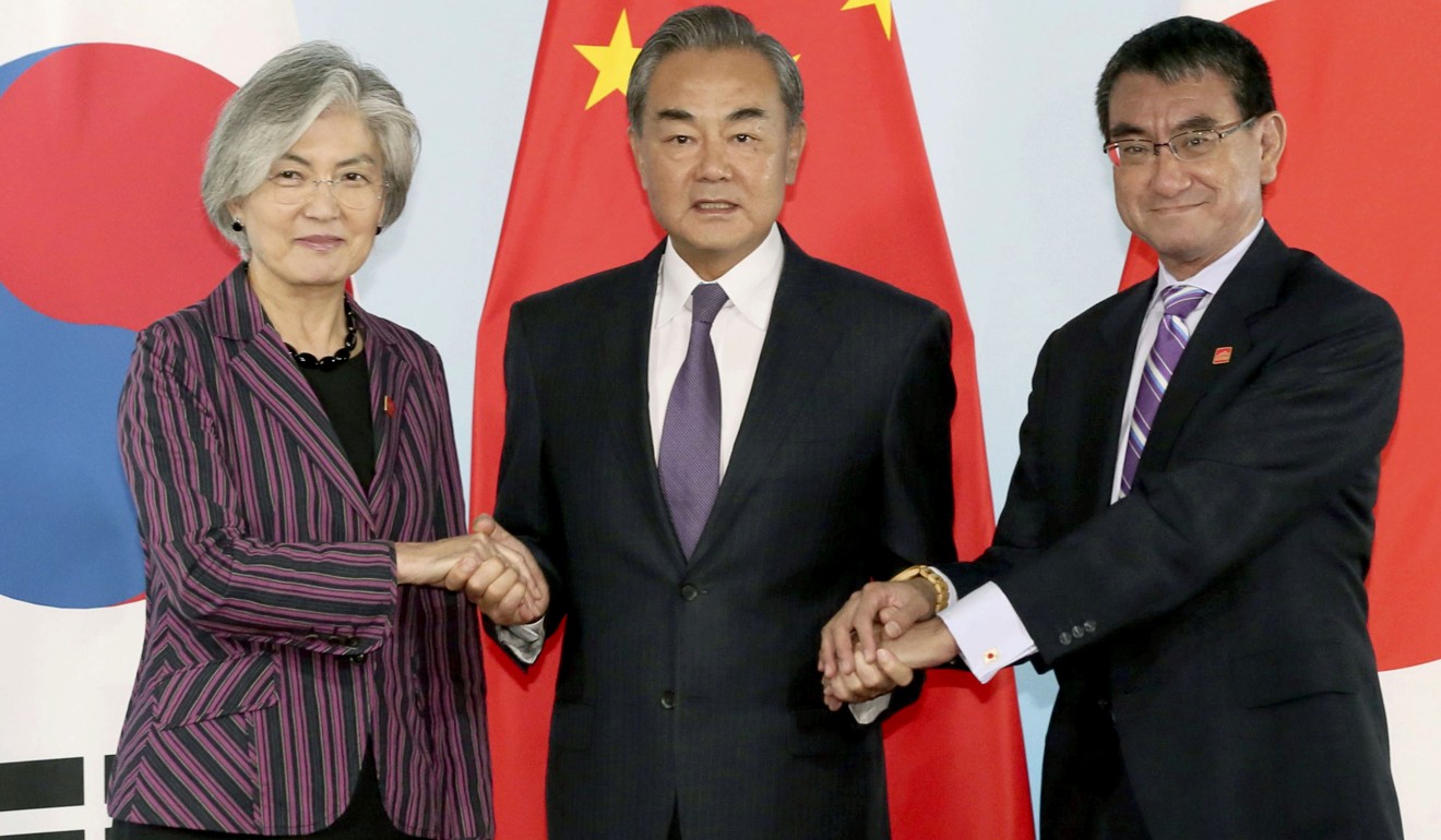 Chinese Foreign Minister Wang Yi holds the hands of his South Korean counterpart Kang Kyung-wha and Japanese counterpart Taro Kono in Beijing. Photo: AP