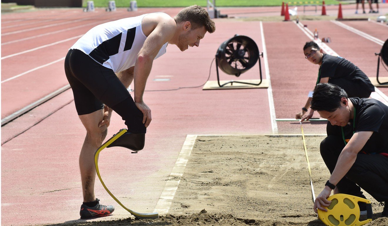 Germany’s Paralympic athlete Markus Rehm looks at officials taking his distance measurement at a long jump demonstration in Tokyo. Photo: AFP