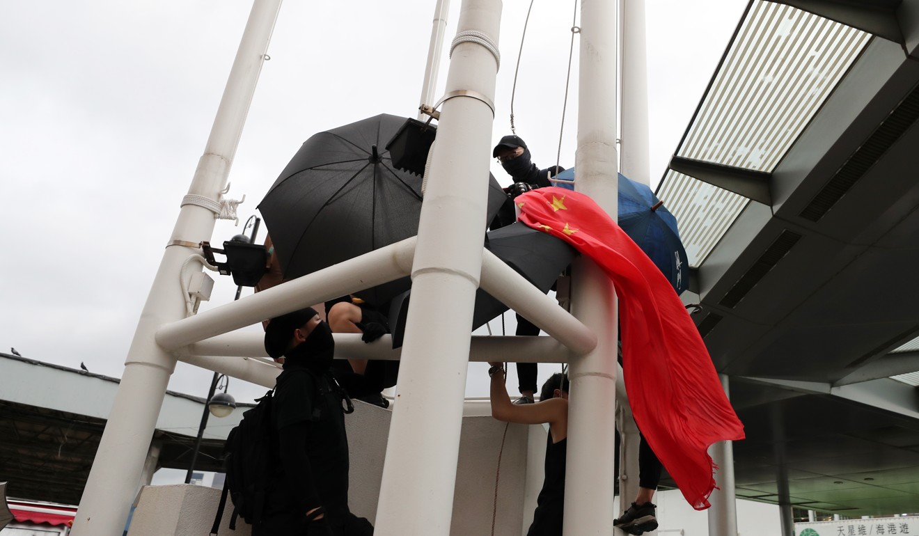 Protesters remove the national flag from a flagpole in Tsim Sha Tsui. Photo: Sam Tsang