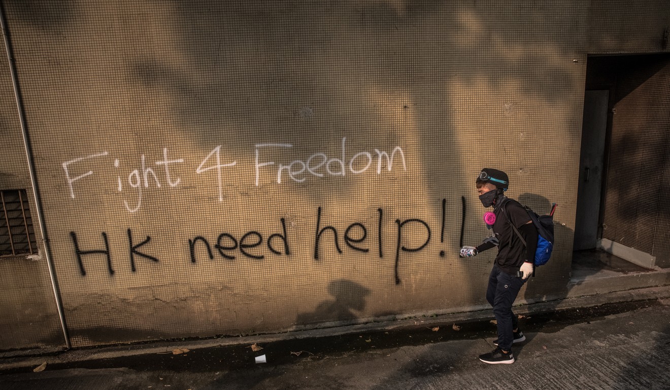 A protester paints graffiti during an march in Kwun Tong on August 24. The protests have evolved into an anti-government movement. Photo: EPA