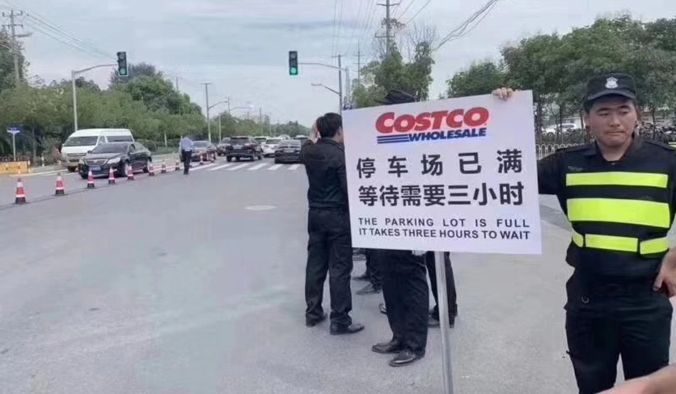 A Costco employee holds up a sign which says that the parking lot is full and will take at least three hours to find one. The US retail giant opened its first Chinese store in Shanghai, on Tuesday. Photo: Handout
