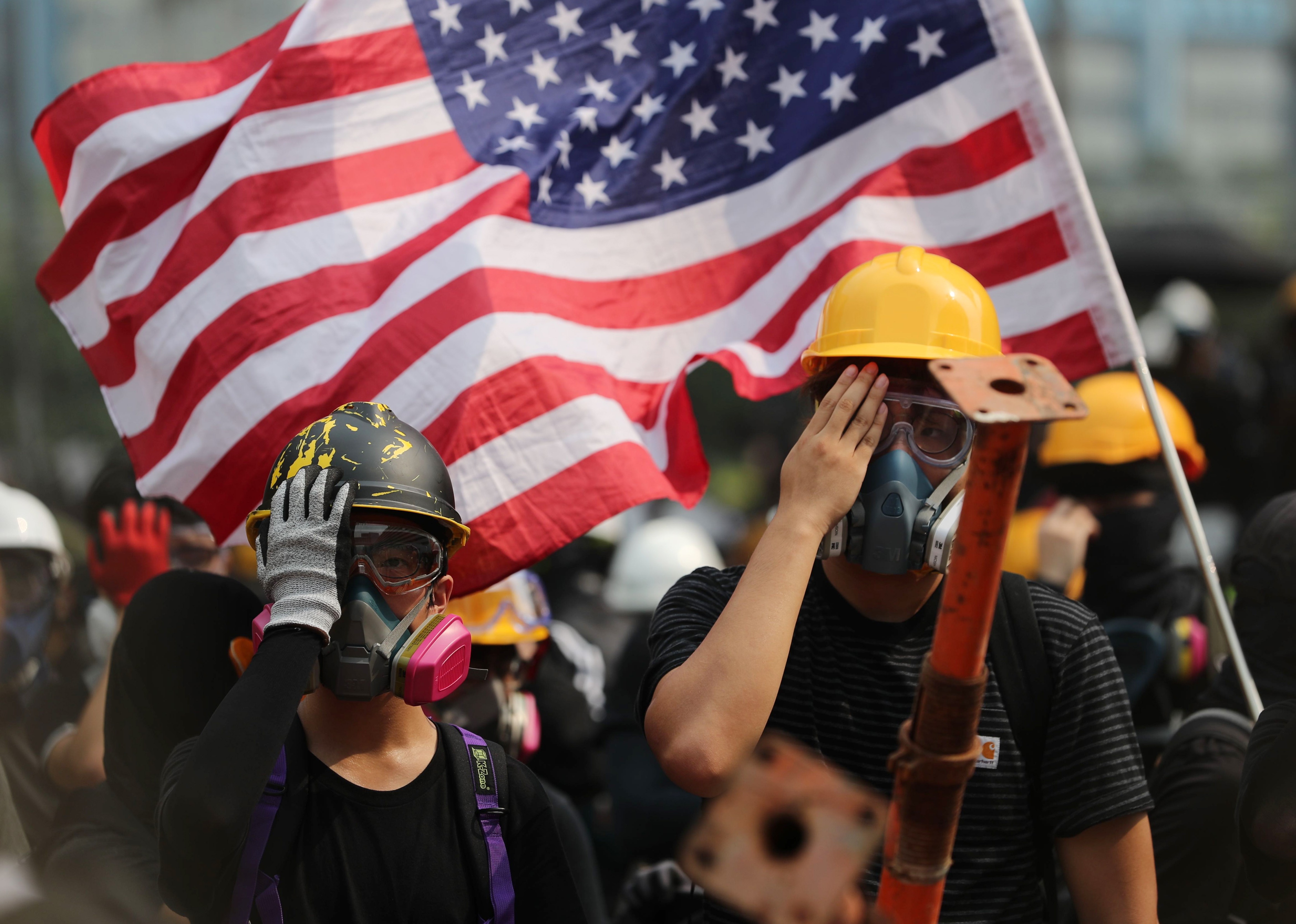 Protesters in the Ngau Tau Kok area of Hong Kong on August 24 wave the US flag, as others cover their right eye in tribute to a woman who suffered a serious eye injury during anti-government protests outside a police station two weeks before. Photo: Sam Tsang