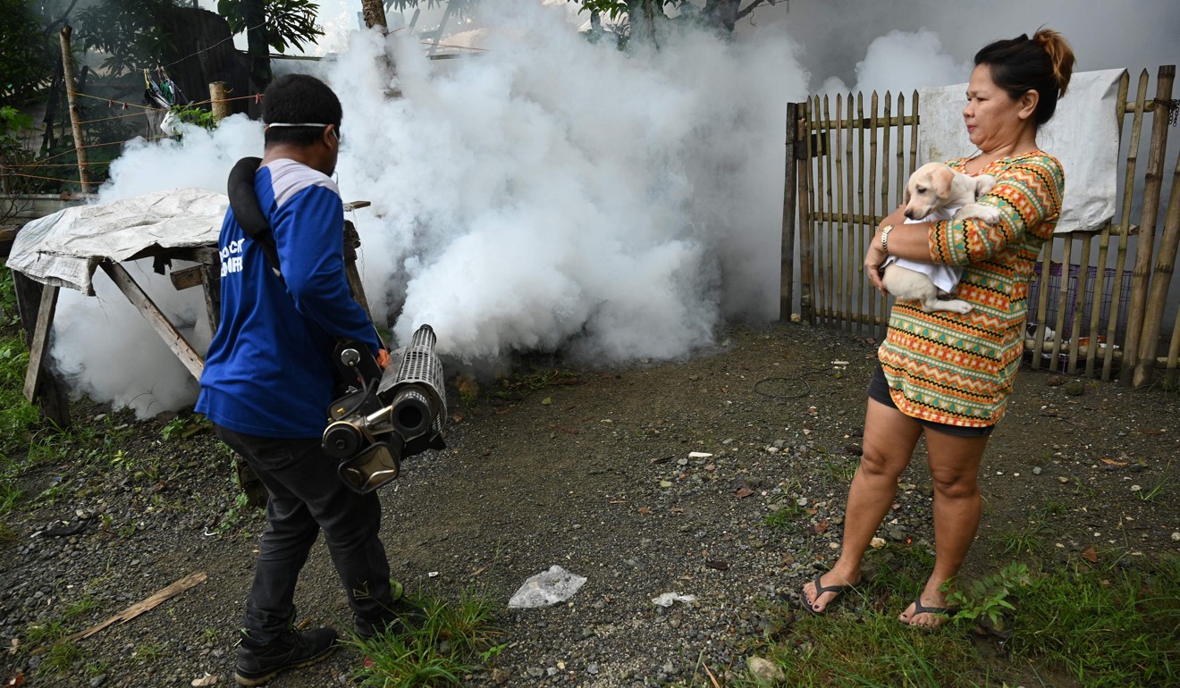 A resident watches as a municipal employee uses a fog machine to kill mosquito larvae in Antipolo town, Rizal province. Photo: AFP