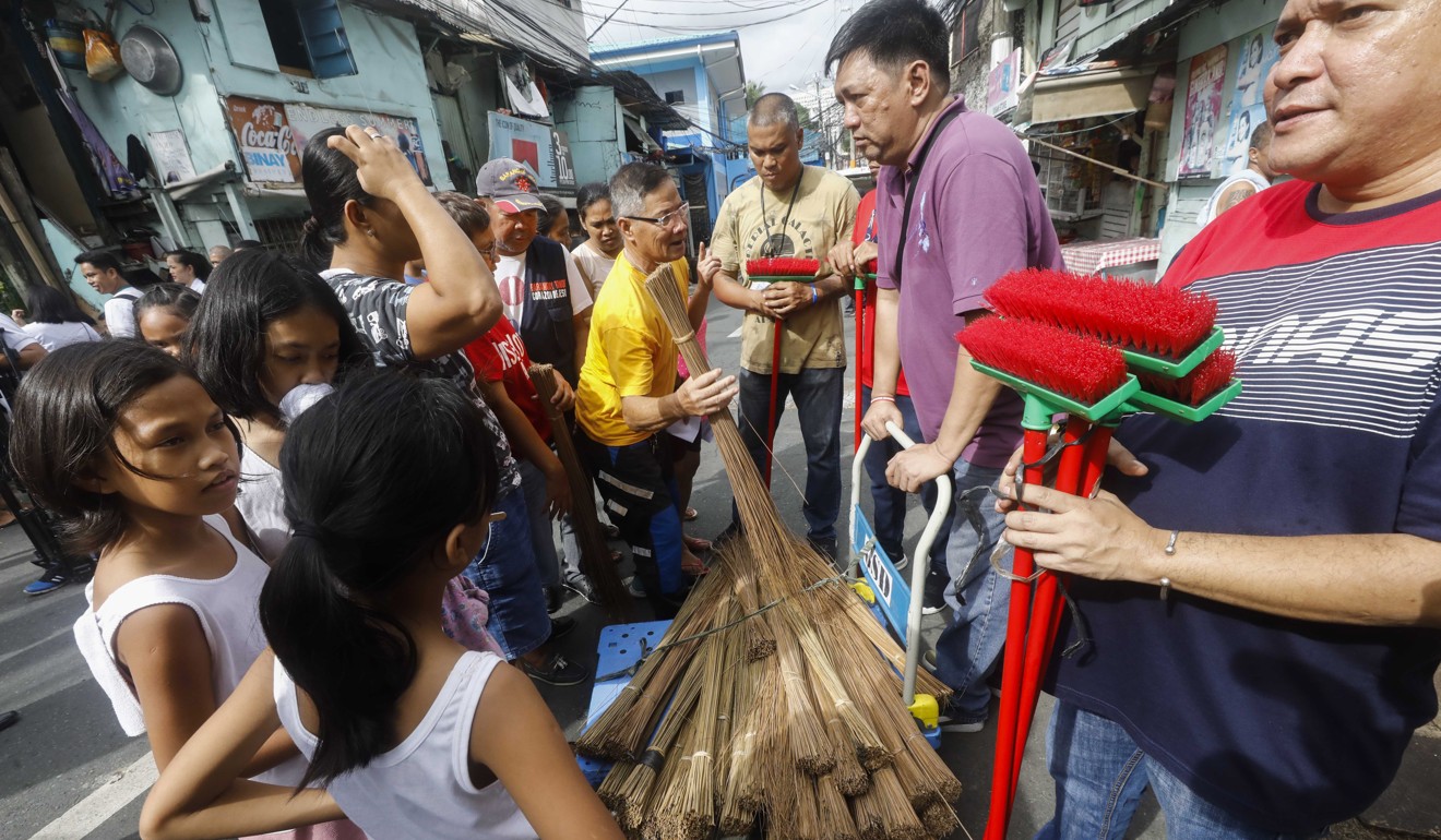 Residents get free brooms as part of a dengue prevention campaign in San Juan City, east of Manila. Photo: EPA-EFE