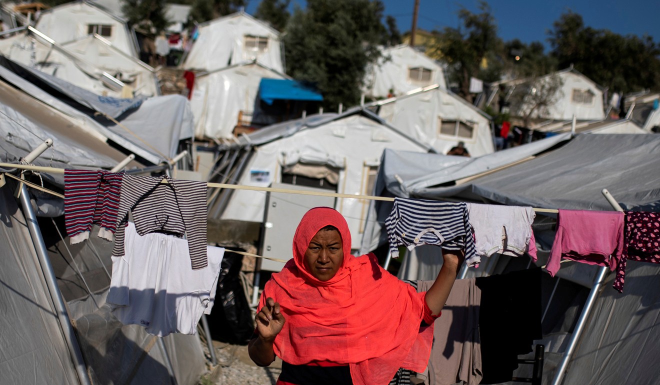 A migrant woman walks among tents at a makeshift camp for refugees and migrants next to the Moria camp on Lesbos. Photo: Reuters