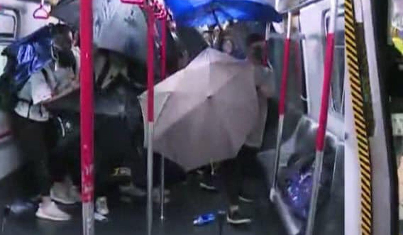 Passengers open their umbrellas to protect themselves after ‘raptors’ stormed onto an MTR train and beat four commuters. Photo: TVB