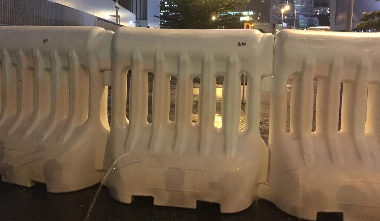 Water pouring out of holes poked into police barricades. Photo: Kanis Leung