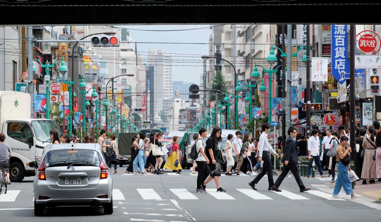 People cross a street in Shin-Okubo district in Tokyo. Photo: AFP