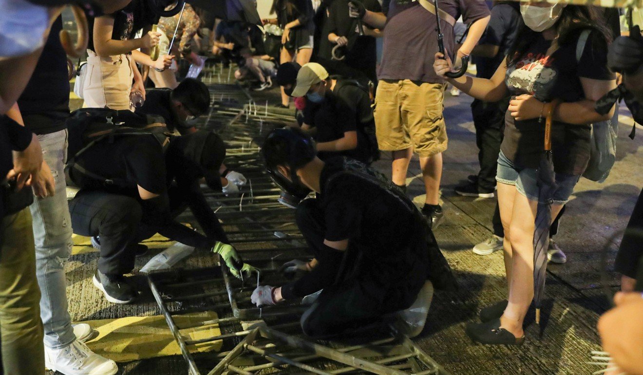 Protesters dismantling metal road railings to make a blockade. Photo: Sam Tsang