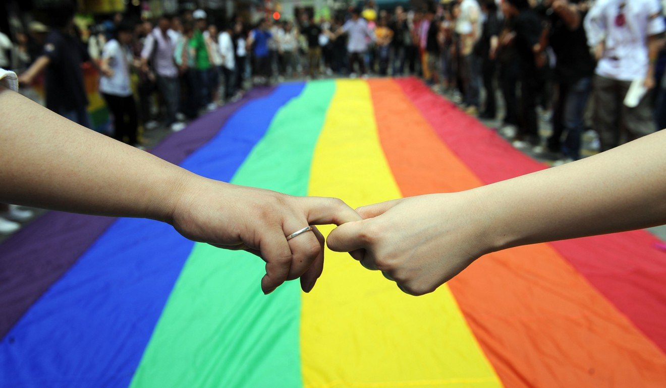 Gay and lesbian activists form a human chain around a rainbow flag during celebrations marking the fourth annual International Day Against Homophobia in Hong Kong. Photo: AFP