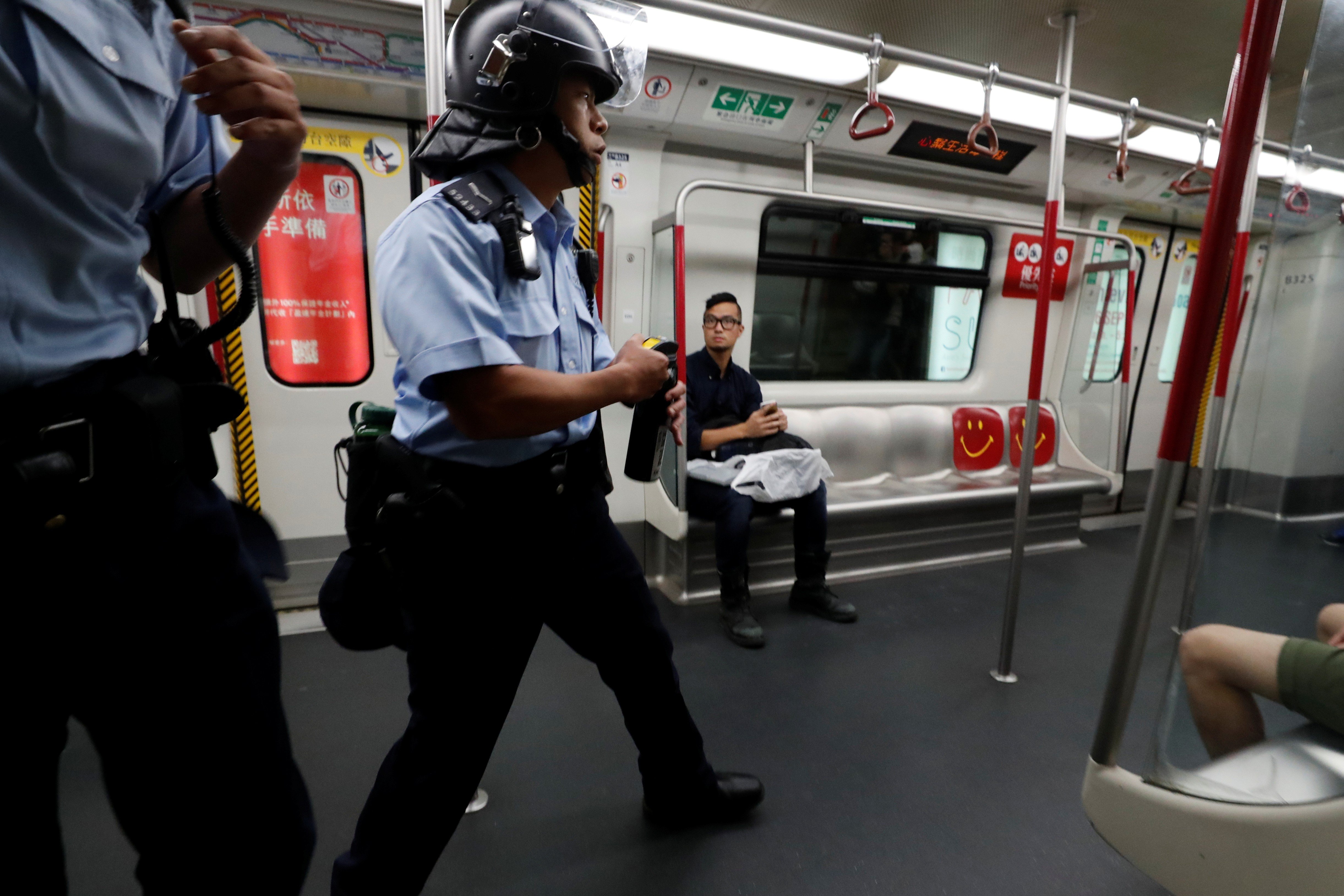 A police officer holds up a can of pepper spray as he searches a Mass Transit Railway train during a protest at Po Lam in Hong Kong. Photo: Reuters