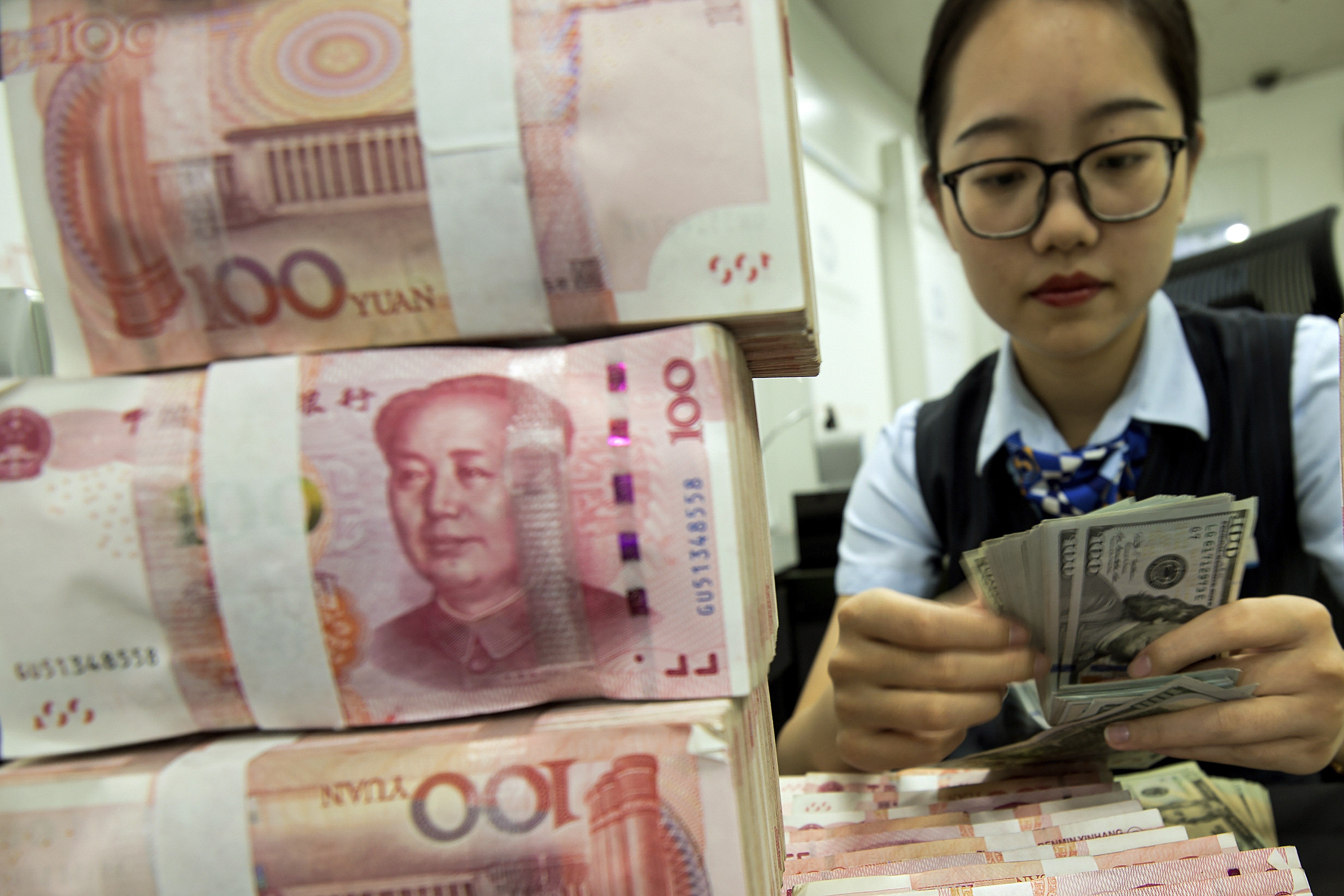A bank employee in Haian, Jiangsu province, counts US dollar banknotes next to a stack of Chinese yuan notes. By accusing China of currency manipulation, the US is ignoring reality and applying double standards. Photo: Chinatopix via AP