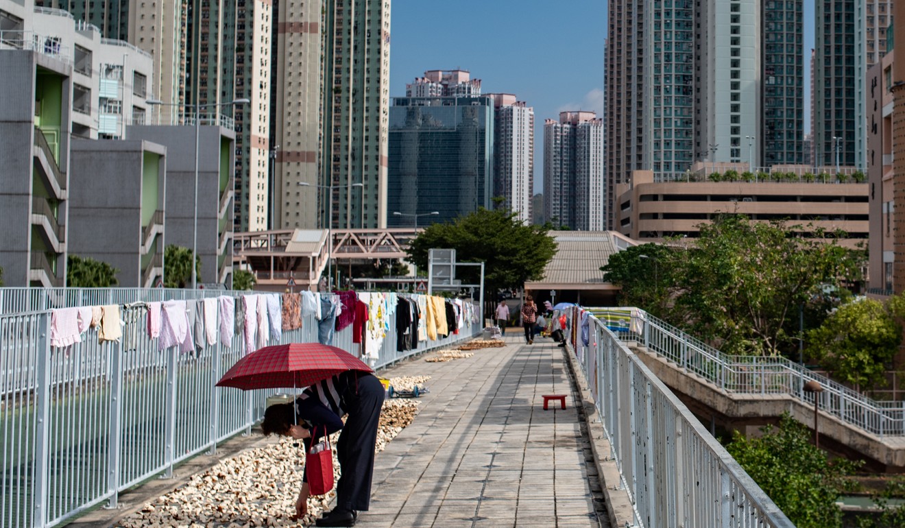 A woman dries preserved orange peels on a footbridge in Tin Shui Wai. Photo: Philip Fong/AFP