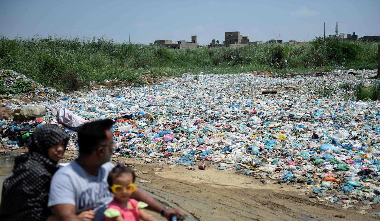A family rides past a garbage dump near a residential area in Karachi. Photo: AFP