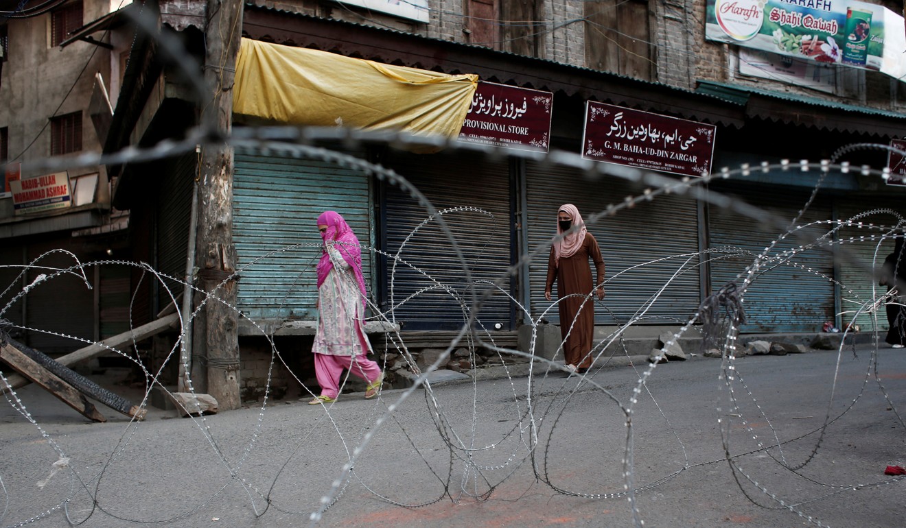 Kashmiri women walk past concertina wire laid across a road during restrictions after the scrapping of the state’s special constitutional status. Photo: Reuters
