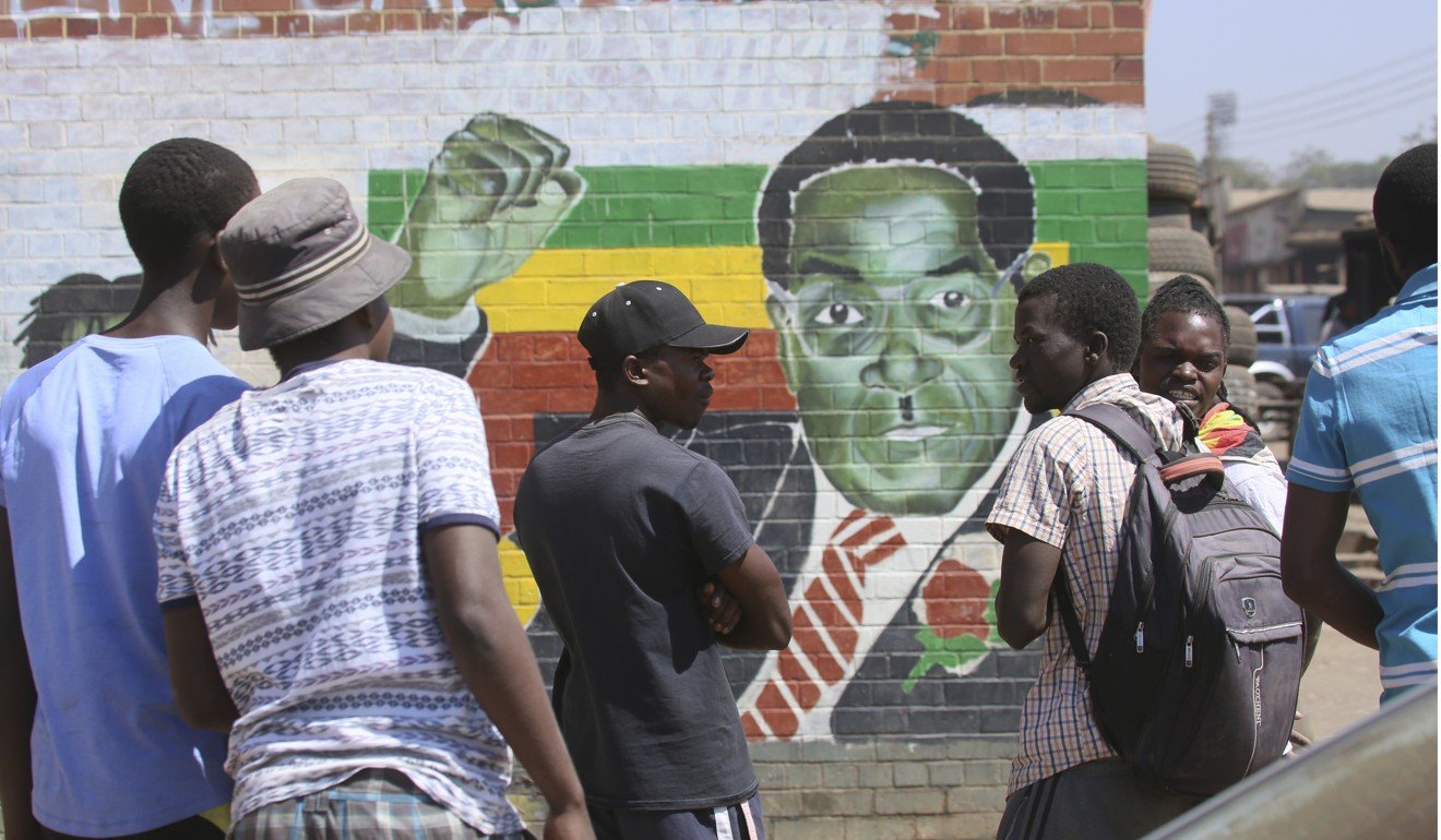 People gather around a portrait of Robert Mugabe in Harare on Friday. Photo: AP