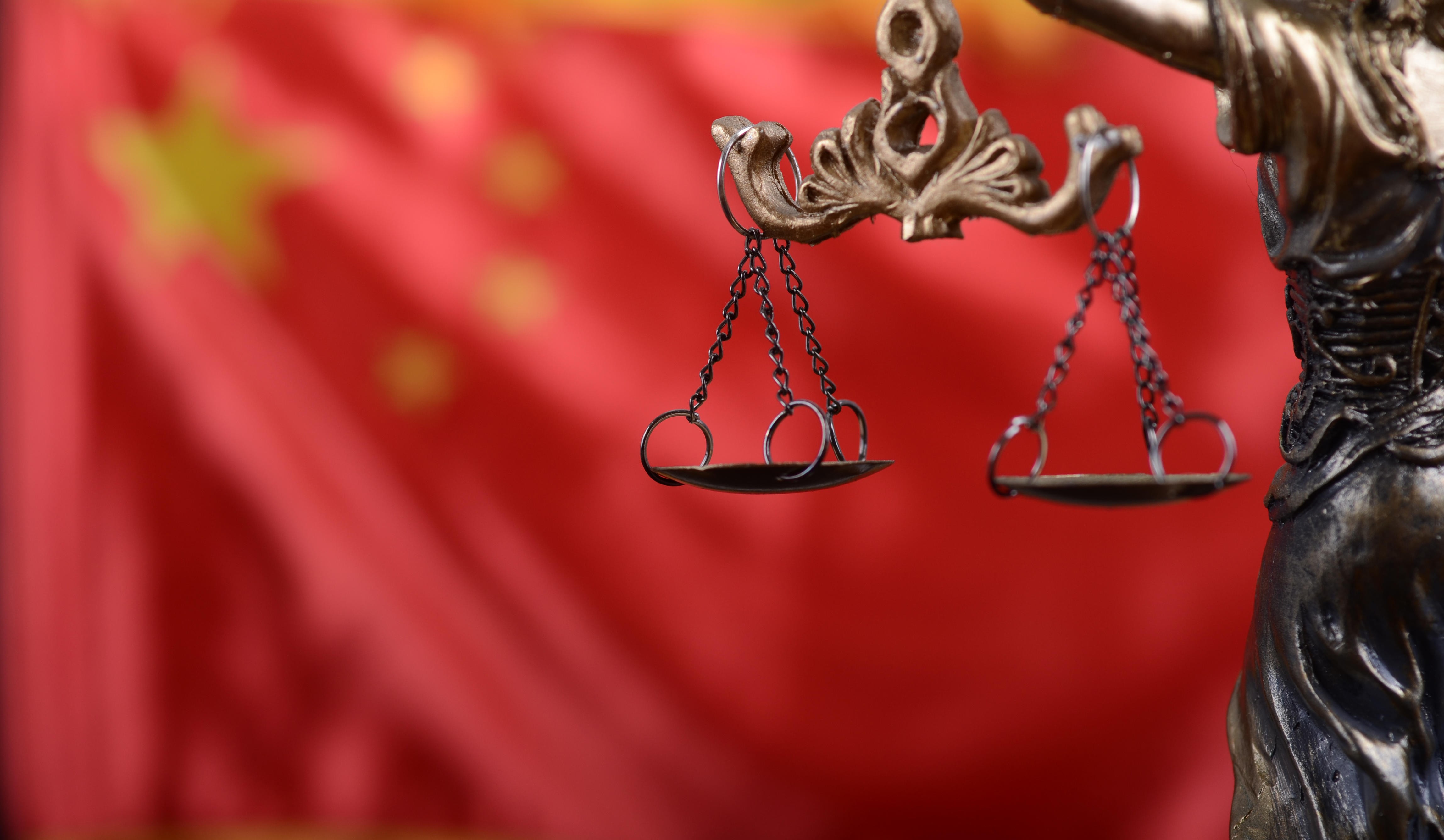 The Scales of Justice and Lady Justice in front of China’s national flag. Photo: Alamy