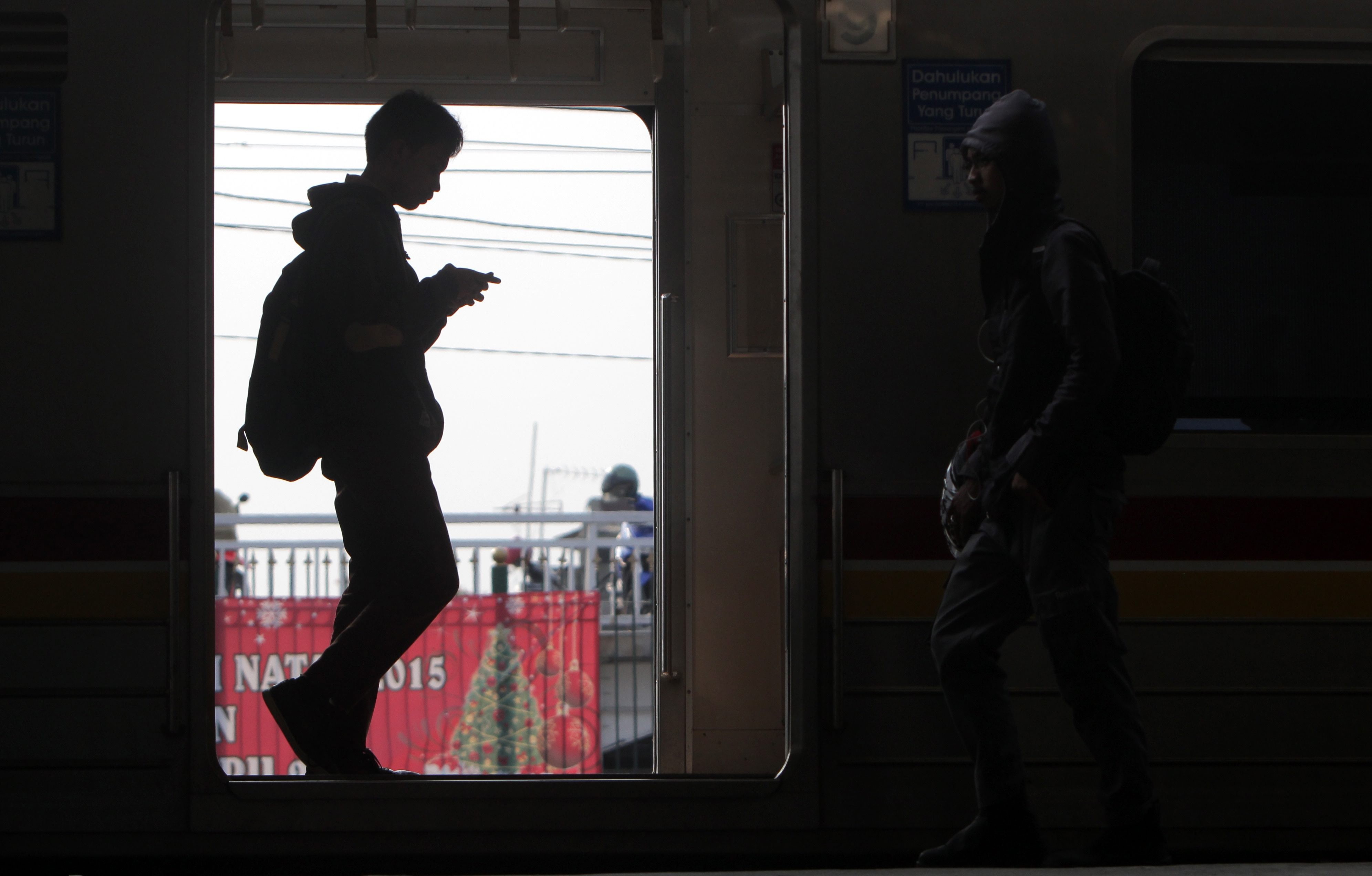 A commuter looking at his mobile phone in Jakarta, Indonesia. Photo: EPA