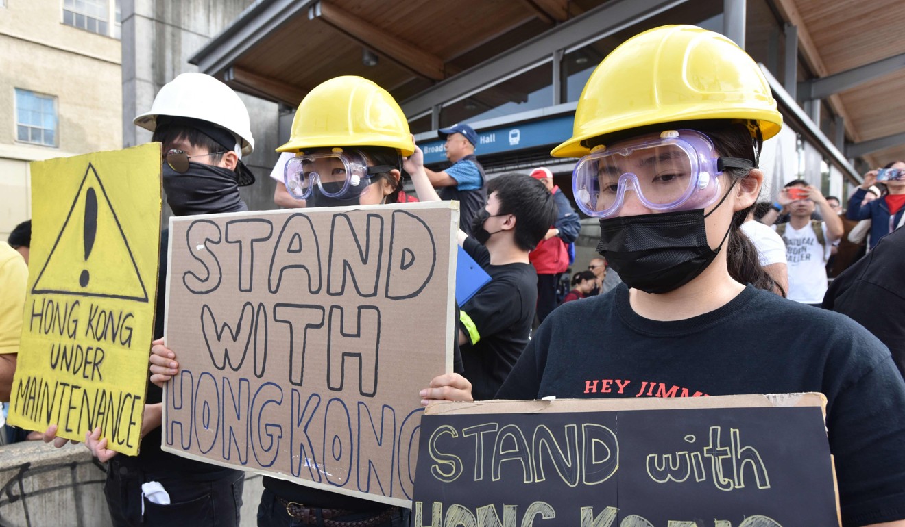 Demonstrators hold signs in support of the Hong Kong democracy movement at the Broadway train station in Vancouver on August 17. Photo: AFP