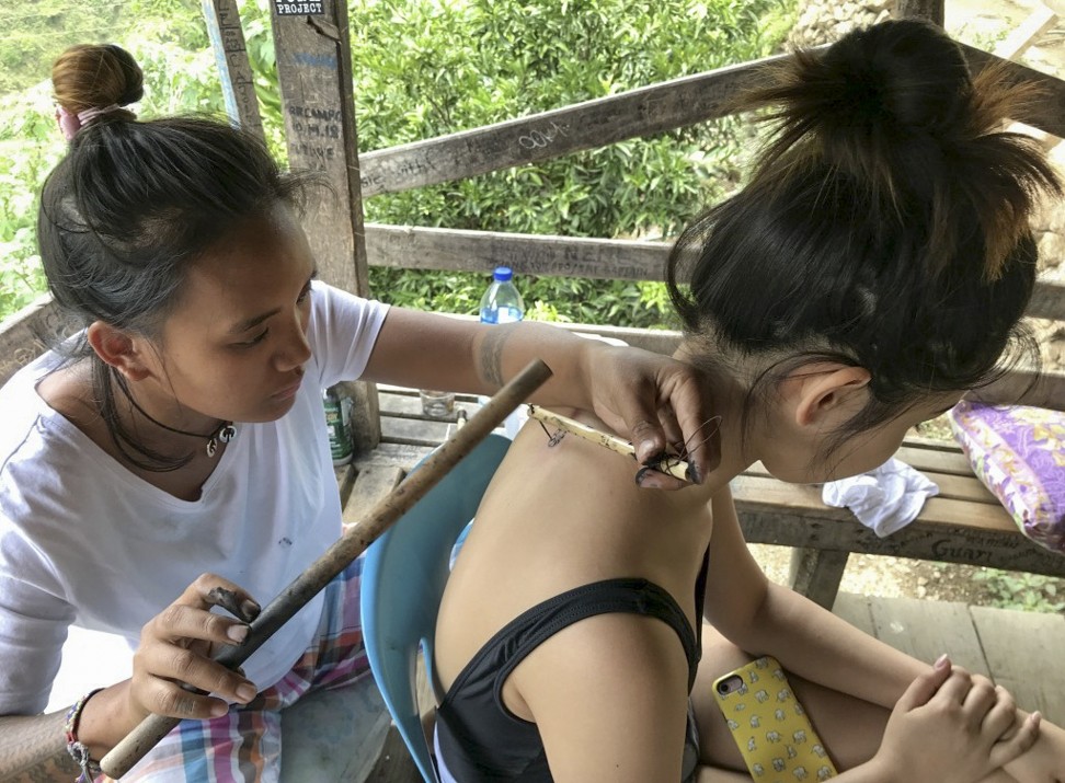 Grace Palicas uses a bamboo hammer, a lemon thorn and charcoal to tattoo Ian Gill’s daughter. Photo: Ian Gill