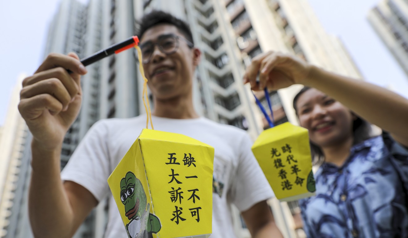 Financial workers hold lanterns outside One Island East in Quarry Bay. Photo: May Tse