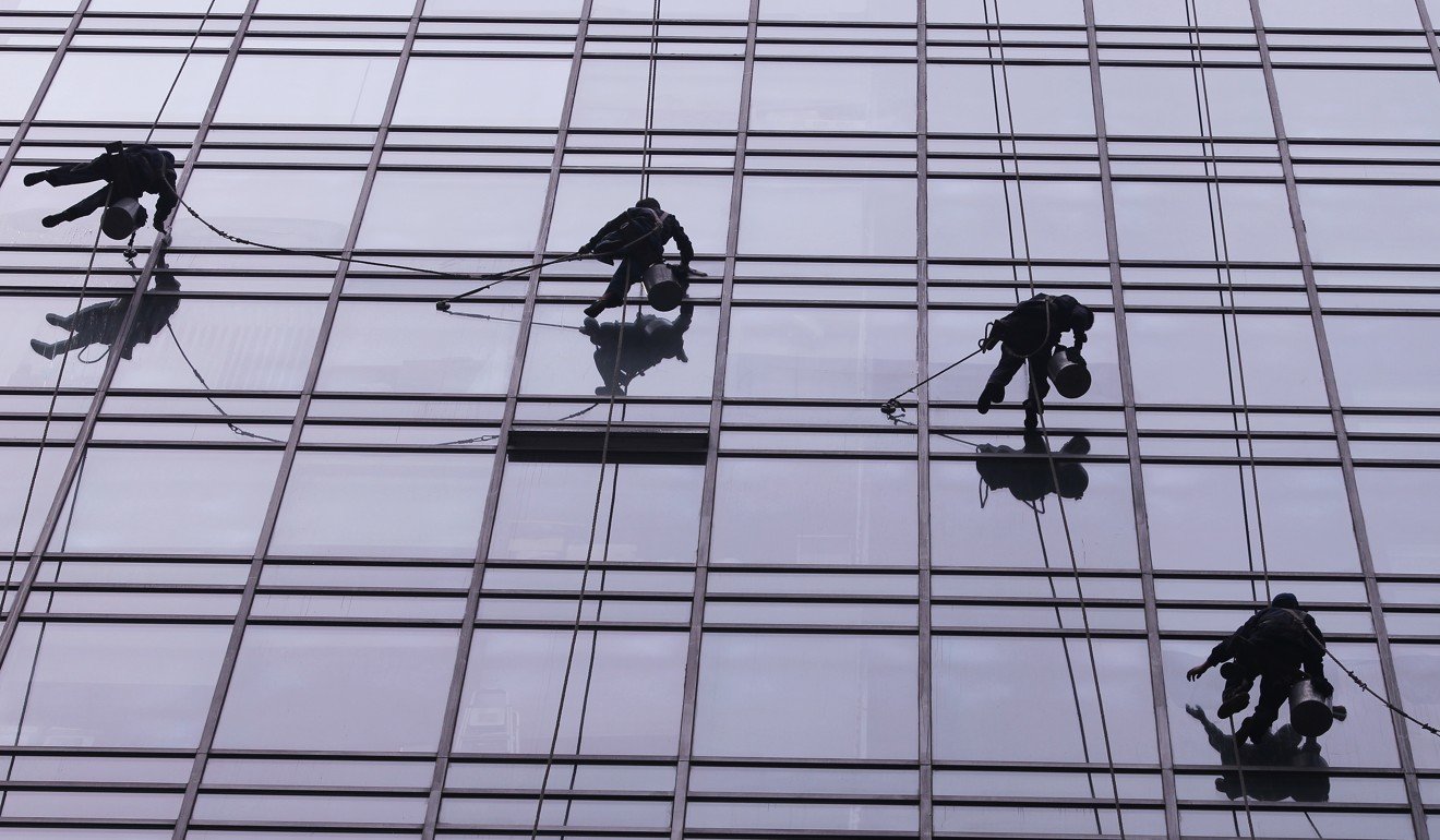 Migrant workers clean windows of a high-rise office building in Beijing. Photo: Simon Song