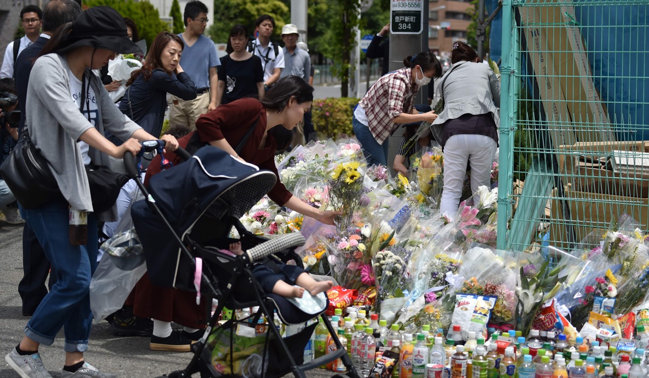 People gather to offer flowers at the crime scene where a man stabbed 19 people, including children, in Kawasaki in May. Photo: AFP
