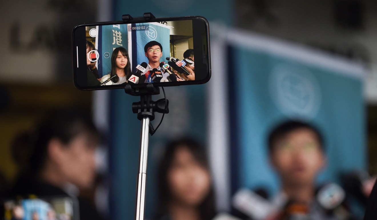 A journalist films pro-democracy activists Agnes Chow and Joshua Wong as they speak to the press after they were released on bail at the Eastern Magistrates’ Courts on August 30. Photo: AFP