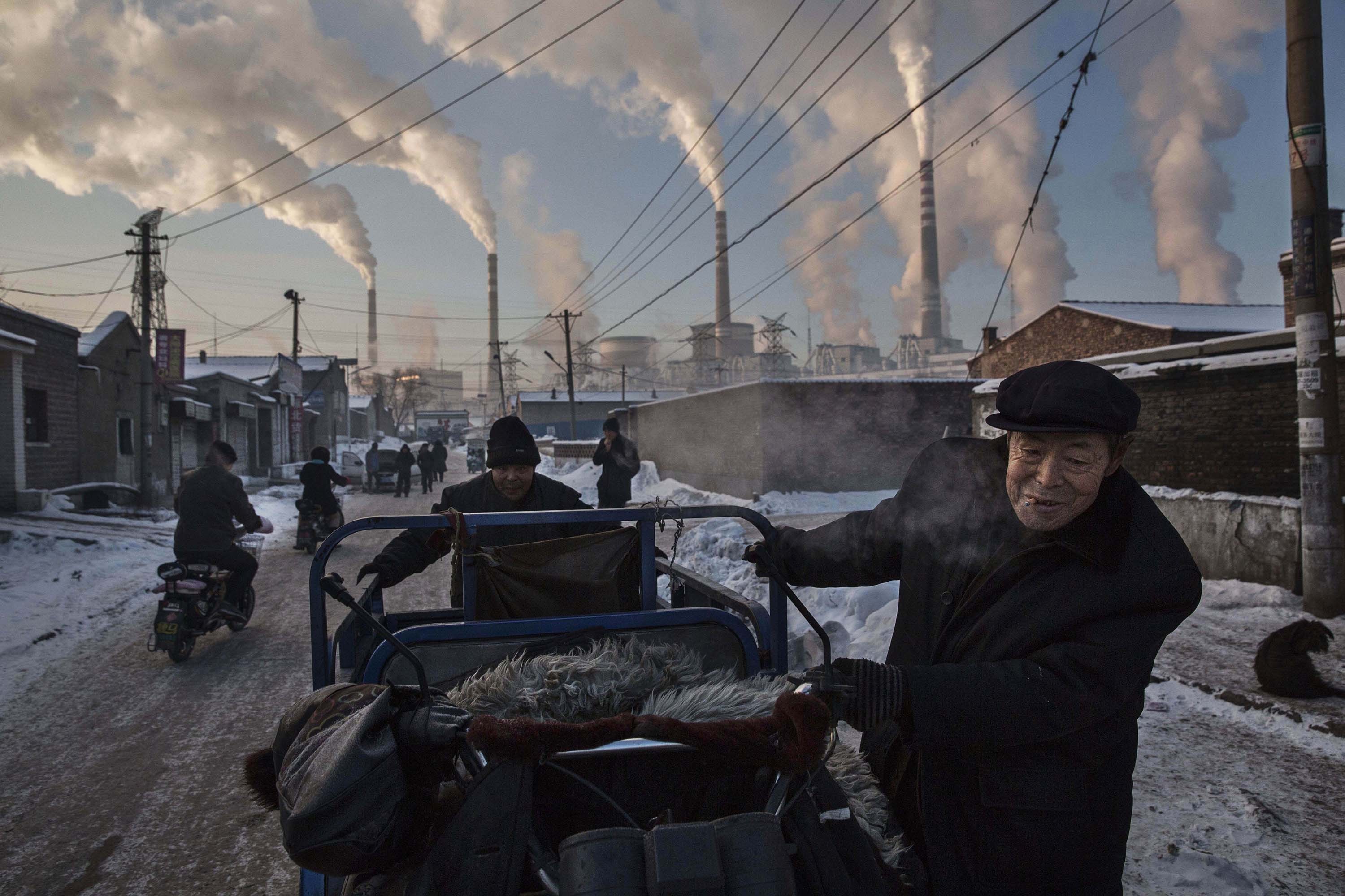 China funds over a quarter of coal power plants with generating capacity of 399 gigawatts under development outside the nation. Here, Chinese men pull a cart in a neighbourhood next to a coal-fired power plant in Shanxi, China, on November 26, 2015. Photo: Associated Press