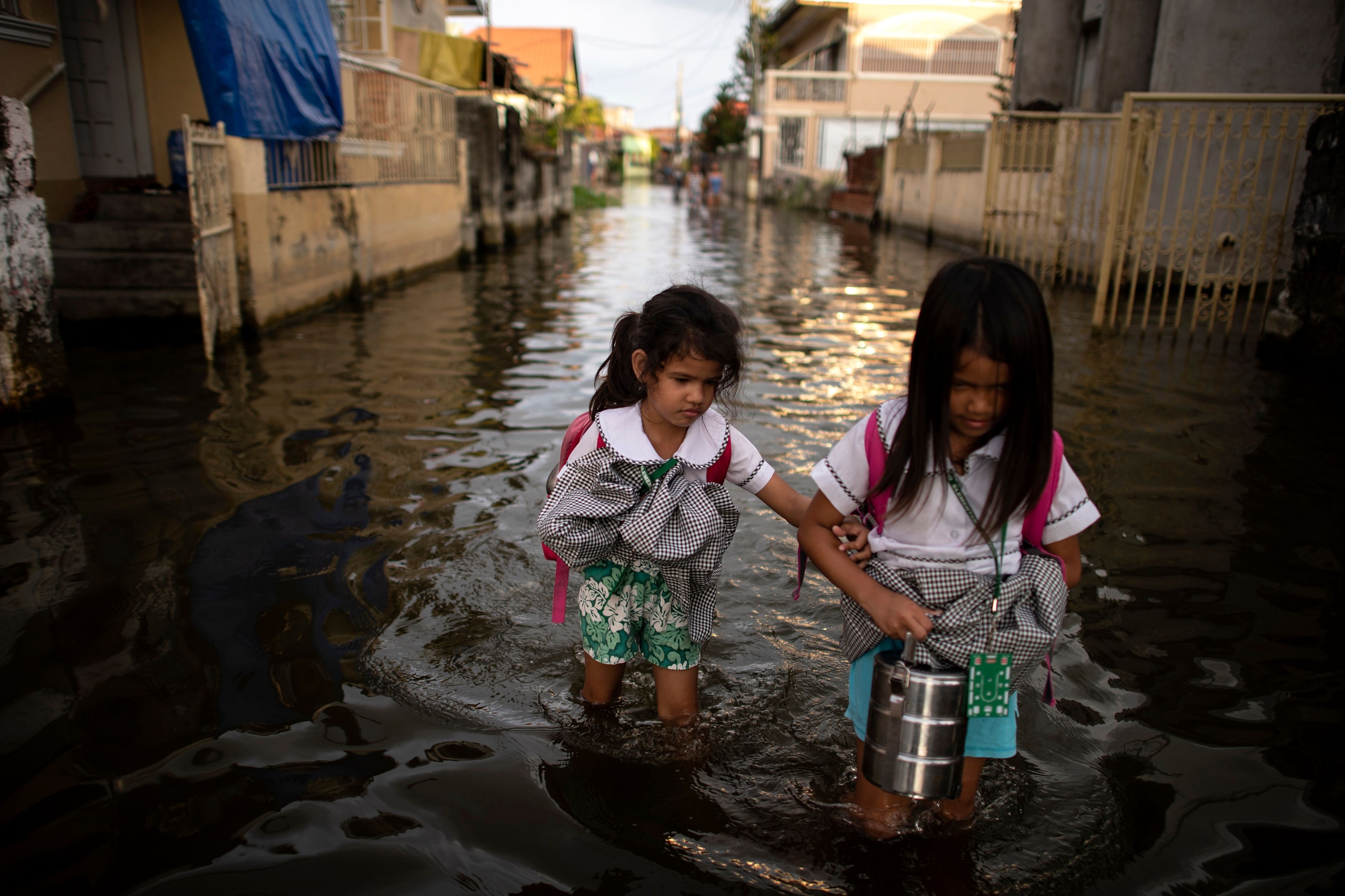 Schoolgirls wade through floodwaters in Pampanga, north of the Philippine capital of Manila, in October last year. Climate-related disasters wreck livelihoods and often force poor parents to take children out of school, entrenching poverty. Photo: AFP