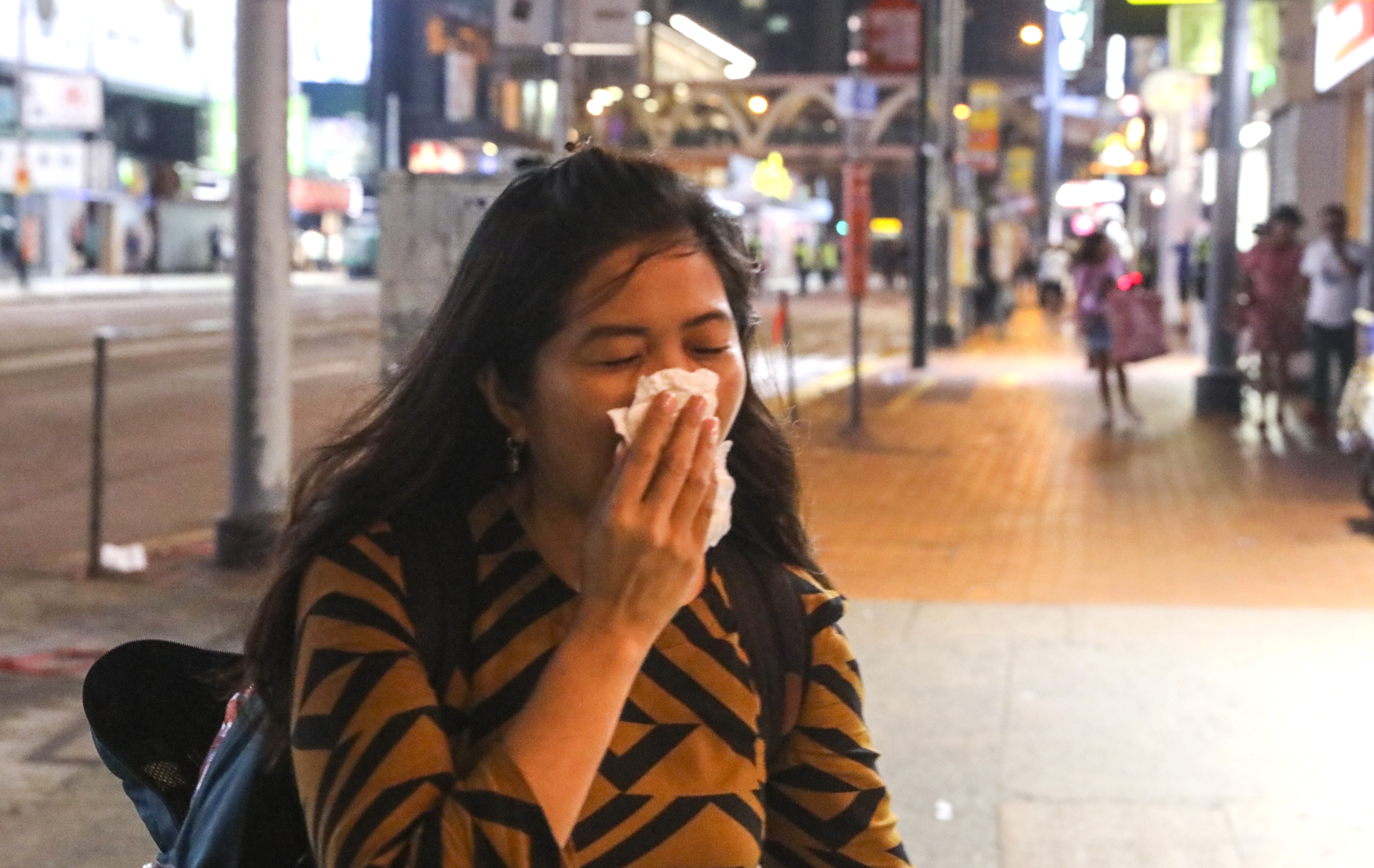 A woman reacts to tear gas in Causeway Bay where railings have been removed by anti-government protesters. Photo: K. Y. Cheng