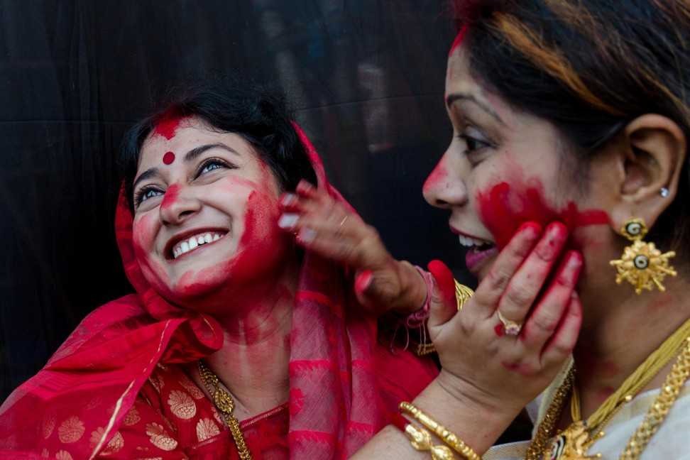 Women smearing each other with sindur, a type of red cosmetic powder, on the final day of Durga Puja. Photo: Alamy