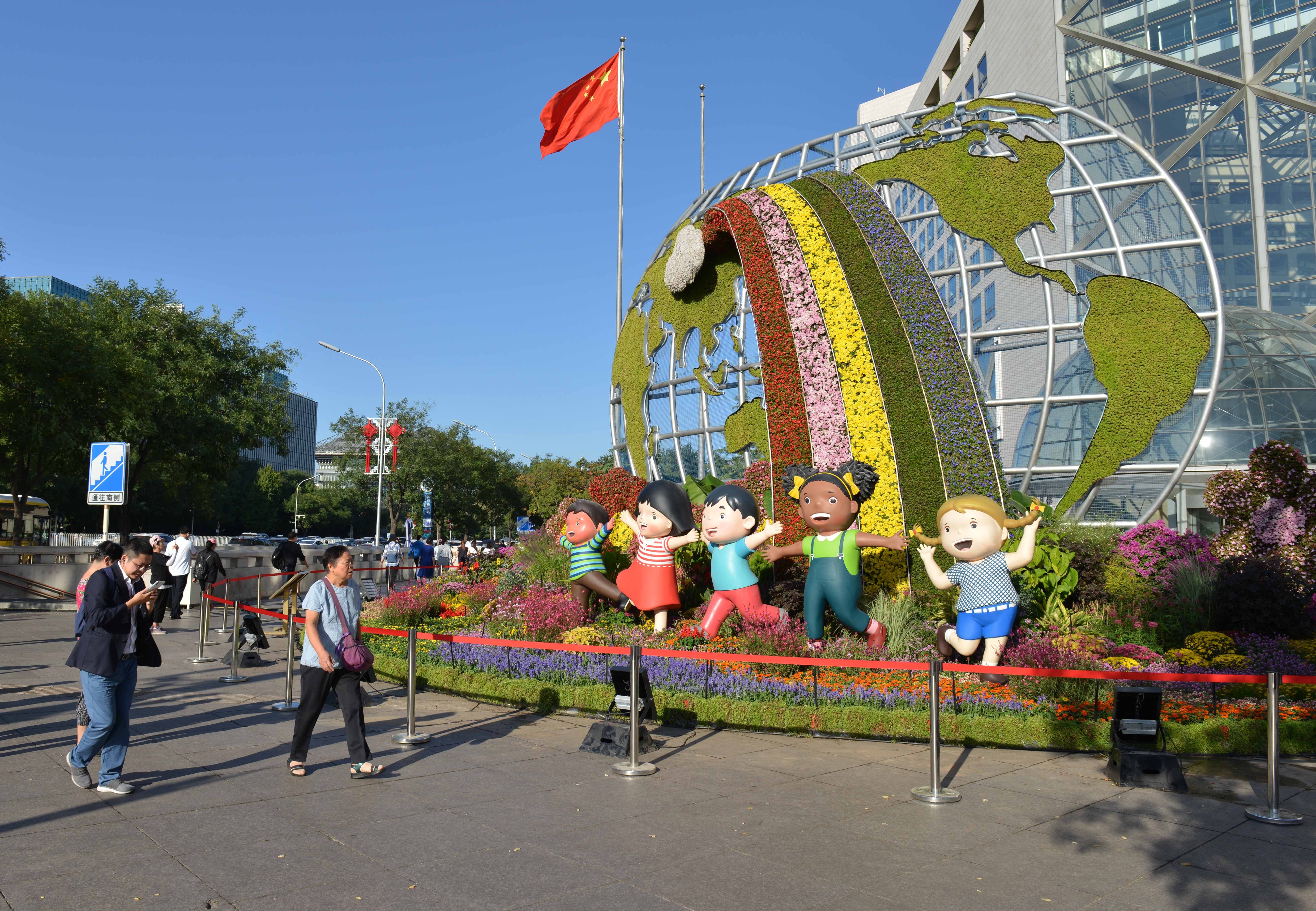 People pass by a flower bed titled “Community with a Shared Future” in Beijing on September 24, one of 12 such beds built along Changan Avenue to celebrate the 70th anniversary of the founding of the People's Republic of China. Photo: Xinhua