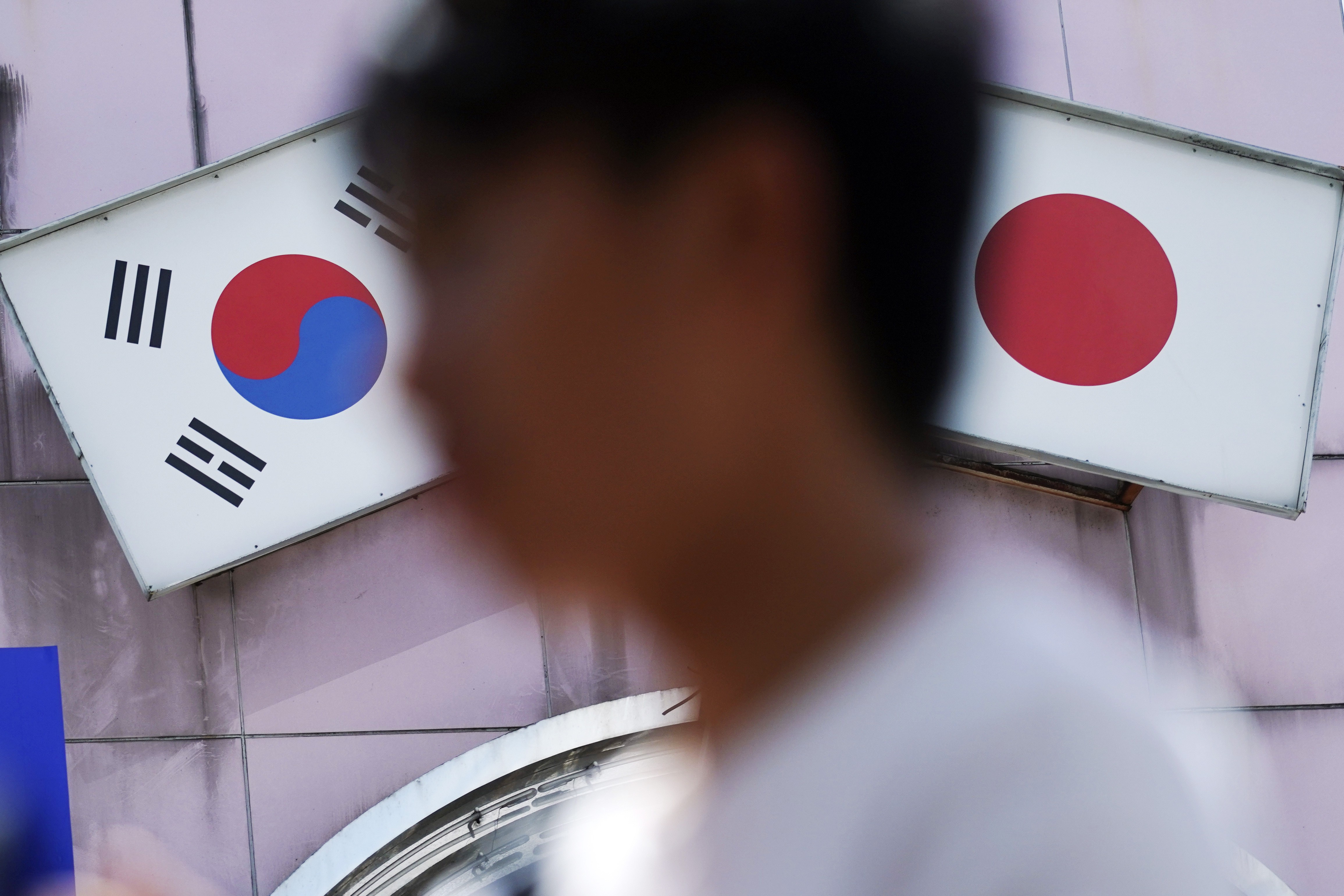 A man walks past an advert featuring Japanese and South Korean flags in Tokyo. Photo: AP