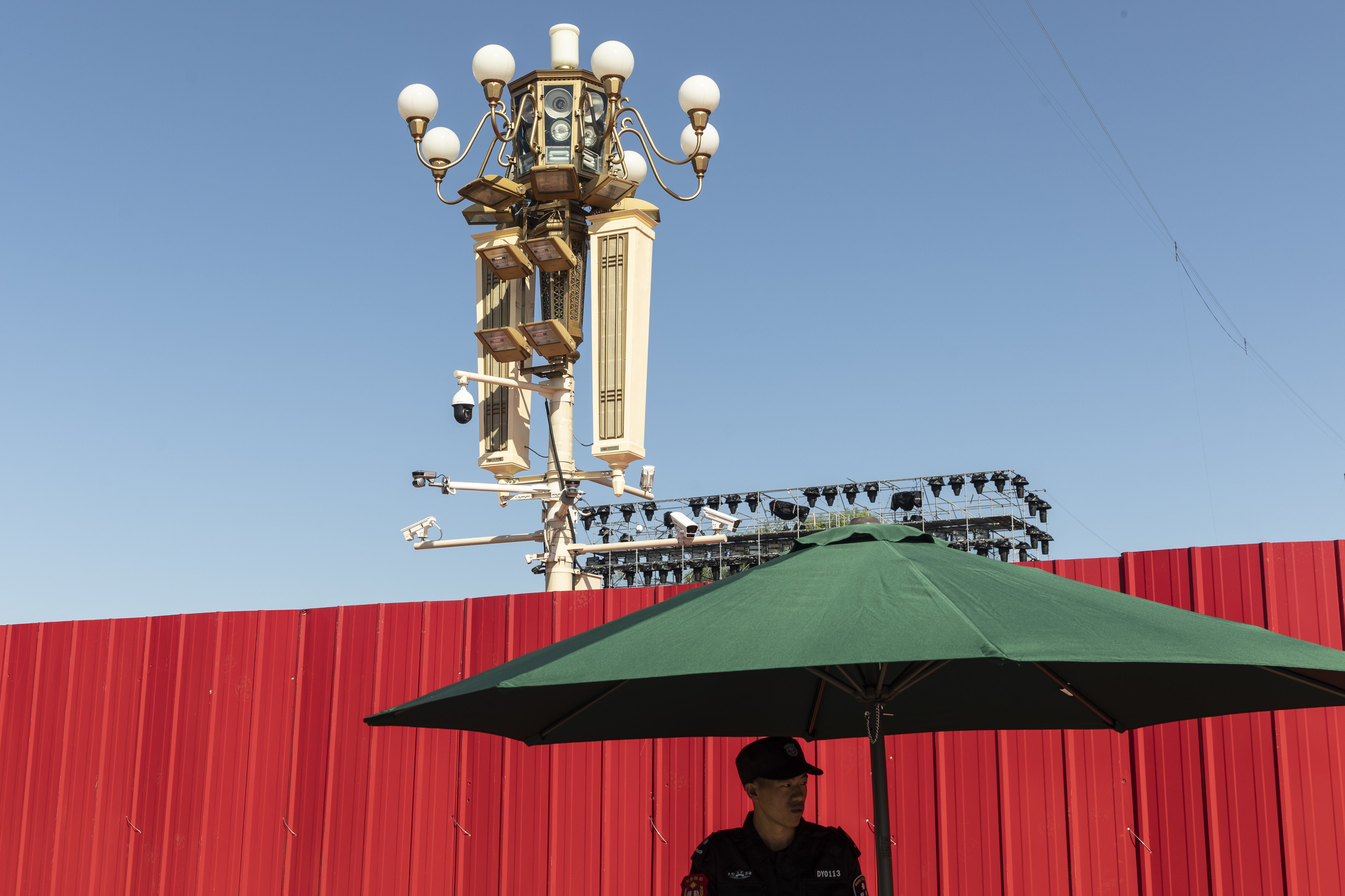 A security guard stands near surveillance cameras on a lamp post at Tiananmen Square in Beijing. Photo: Bloomberg