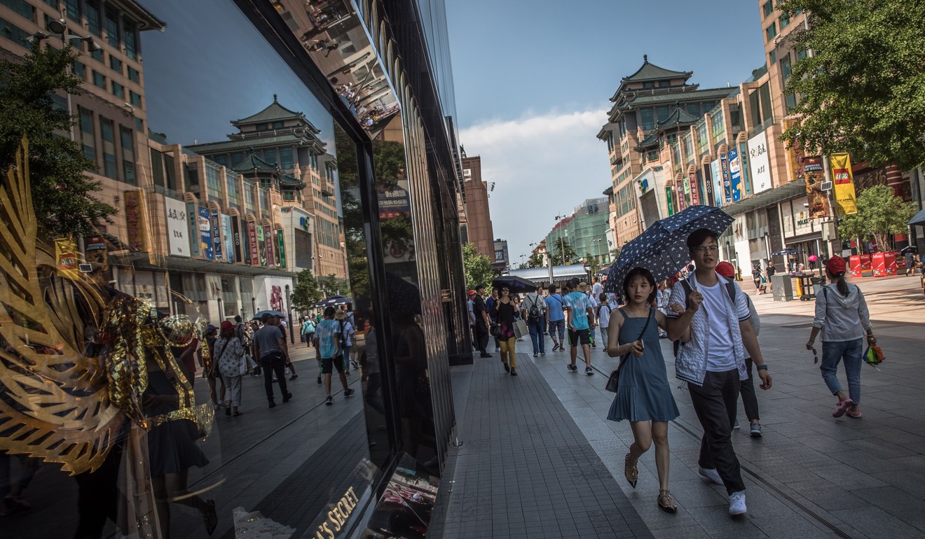Chinese people walk past a Victoria’s Secret store in the Wangfujing shopping district in Beijing. Photo: EPA