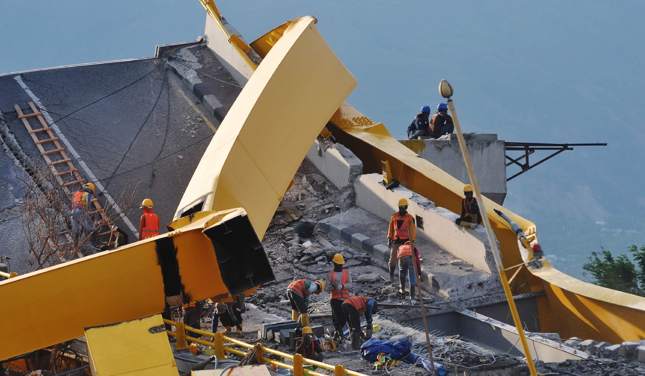 Workers inspect a damaged bridge hit by a quake-tsunami in Palu last year. Photo: AFP