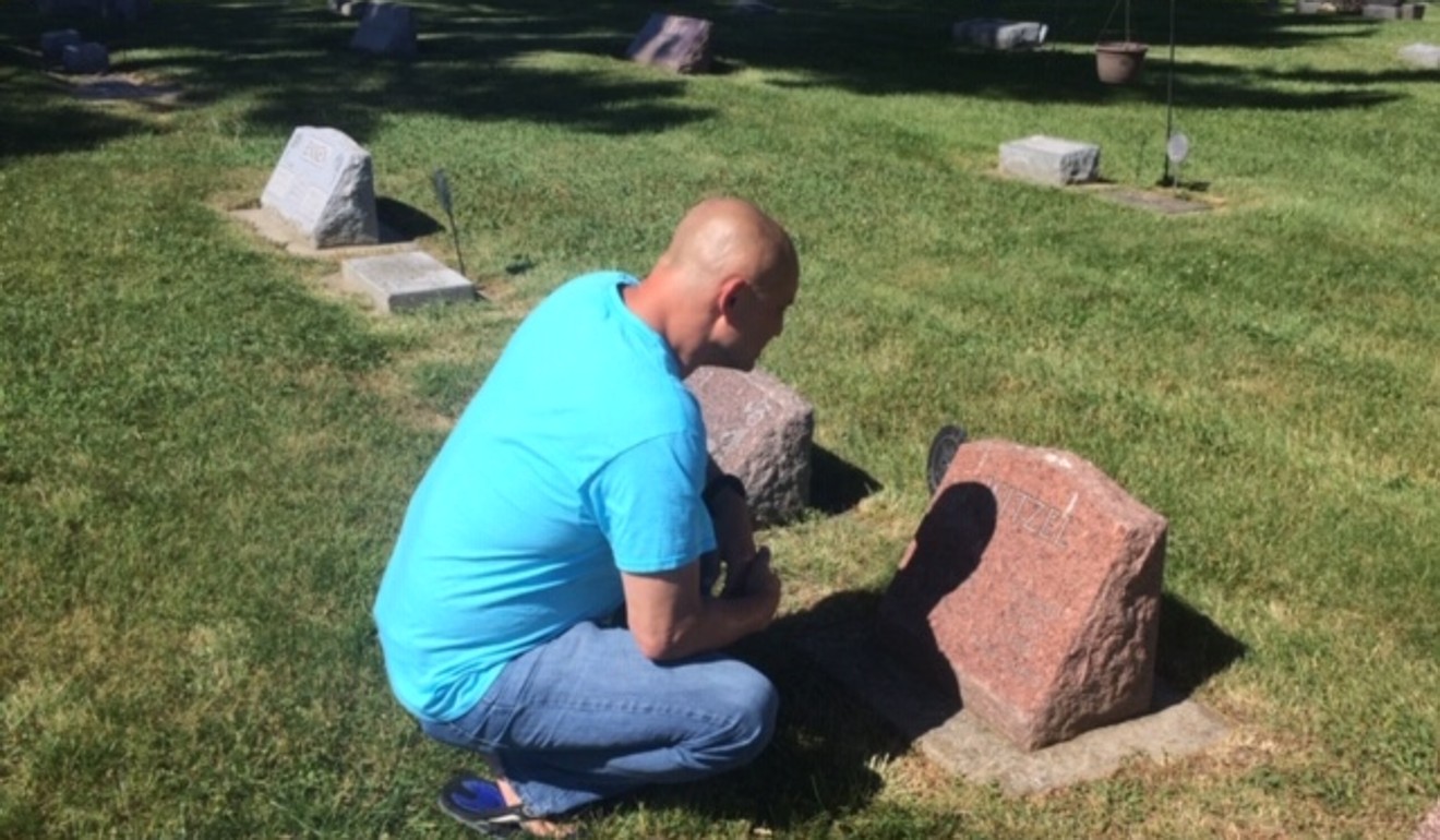 Tony Nguyen pays his respects to Carl Witzel at his tombstone in Ashton, Illinois. Photo courtesy of Coralei Nguyen